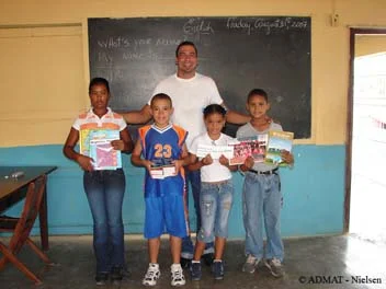 Students holding up the books, dictionaries and money donated by ADMAT and students from the Highbury Primary School in Salisbury, England.