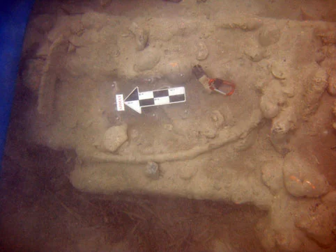 The large concretion of multiple iron ballast bars on the port side. Resting on top are the broken remains of one of the main mast rings