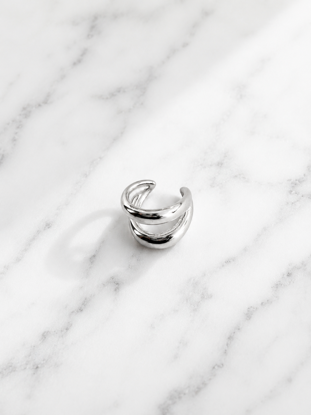 Anneau d’oreille Carina en acier inoxydable argenté sur fond de marbre blanc - Tokade