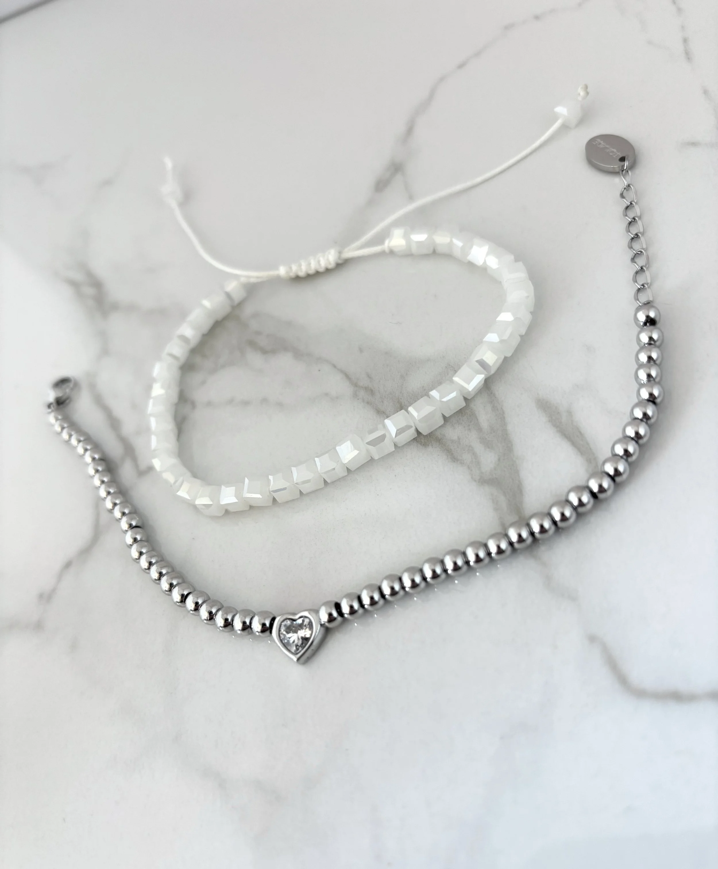 Bracelets acier inoxydable et verre nacré sur fond marbre — duo Tokade