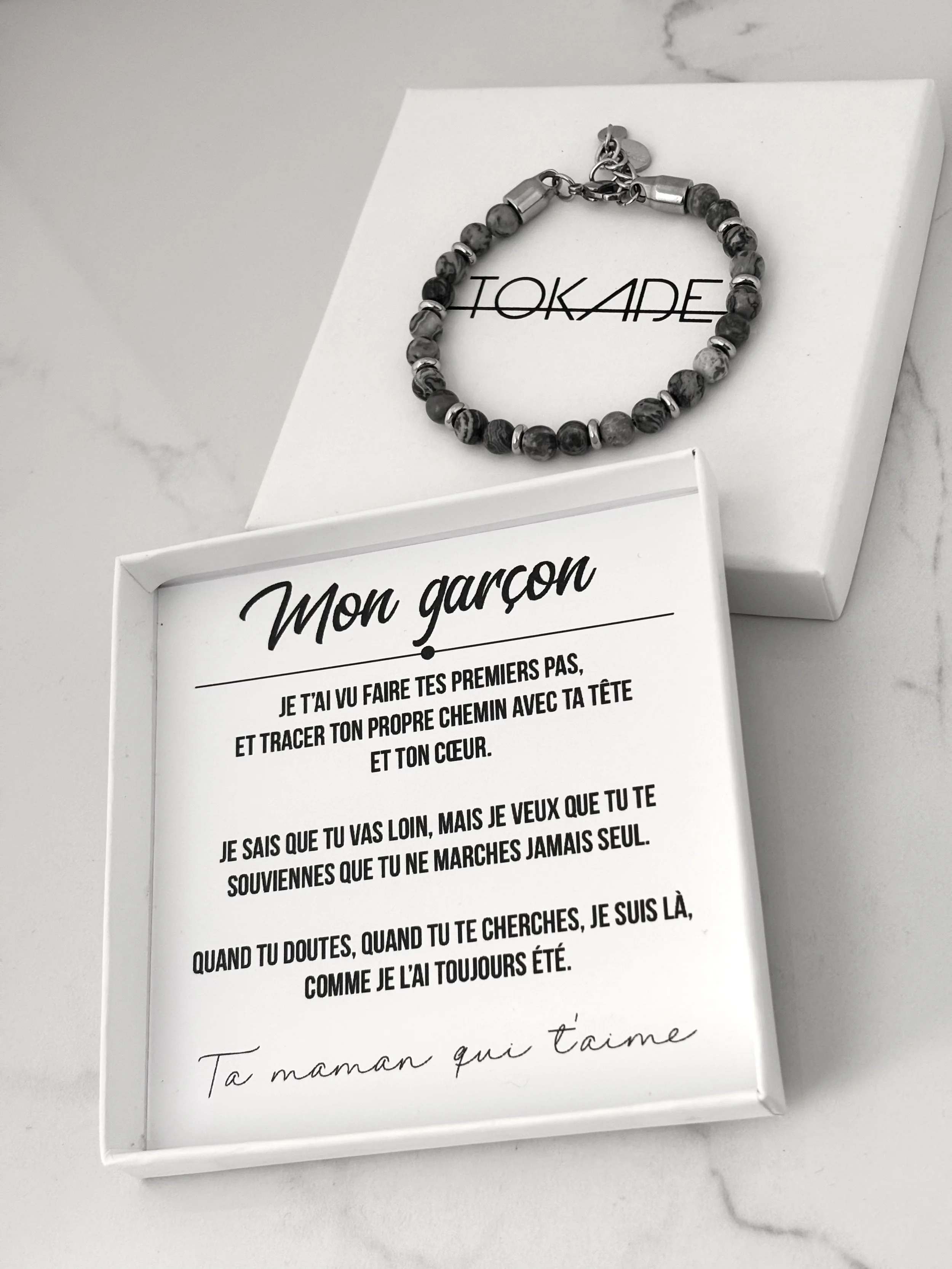 Coffret Tokade blanc incluant le bracelet et le texte touchant à l’intérieur.