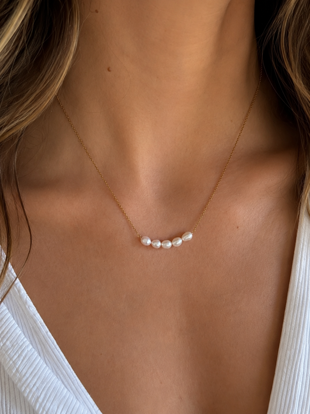 Collier Cristy en perles d’eau douce et acier inoxydable doré porté au cou d’une femme. - Tokade