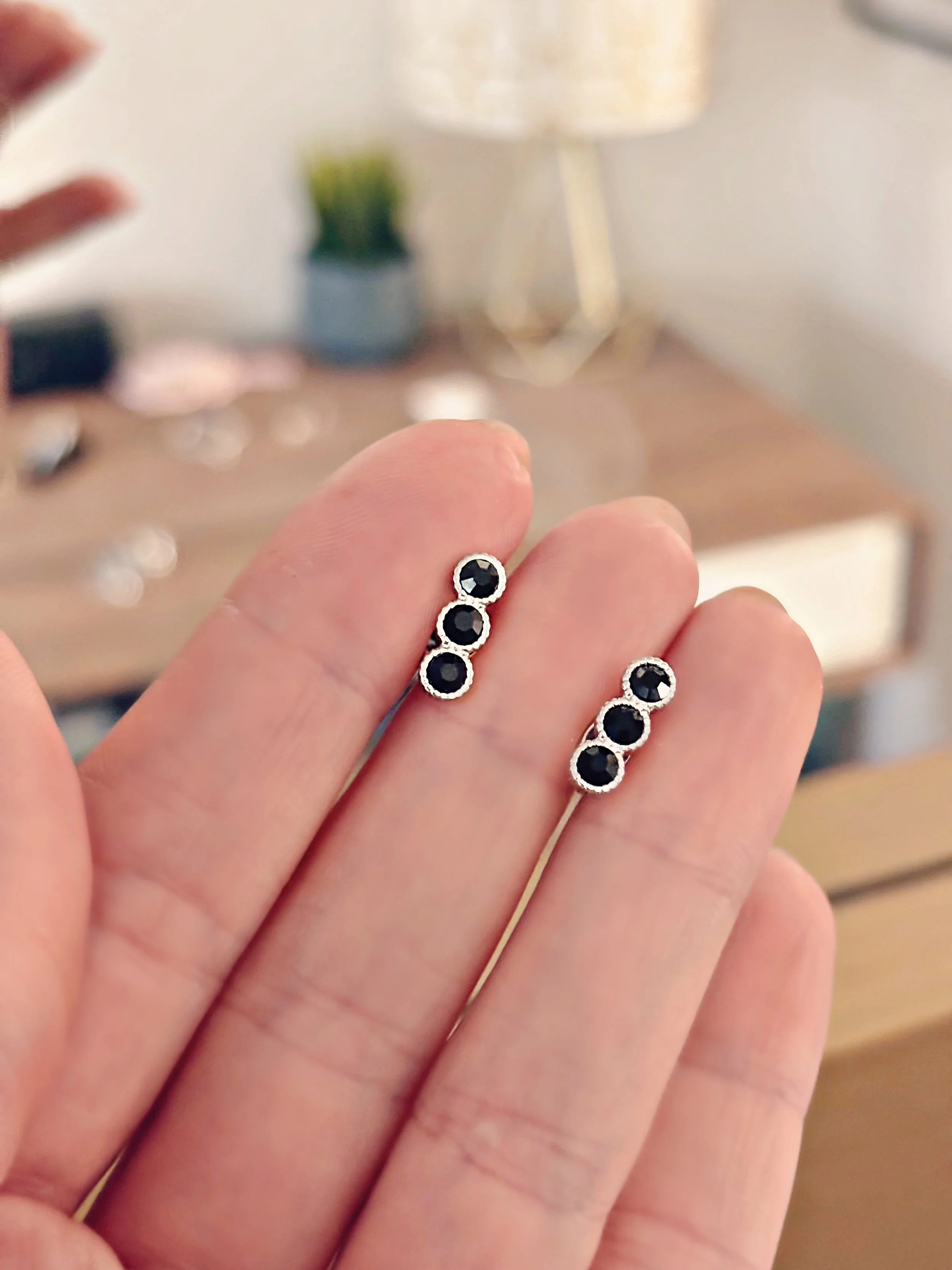 Gros plan des boucles Liora dans la main, vue rapprochée sur les détails des pierres et du métal.