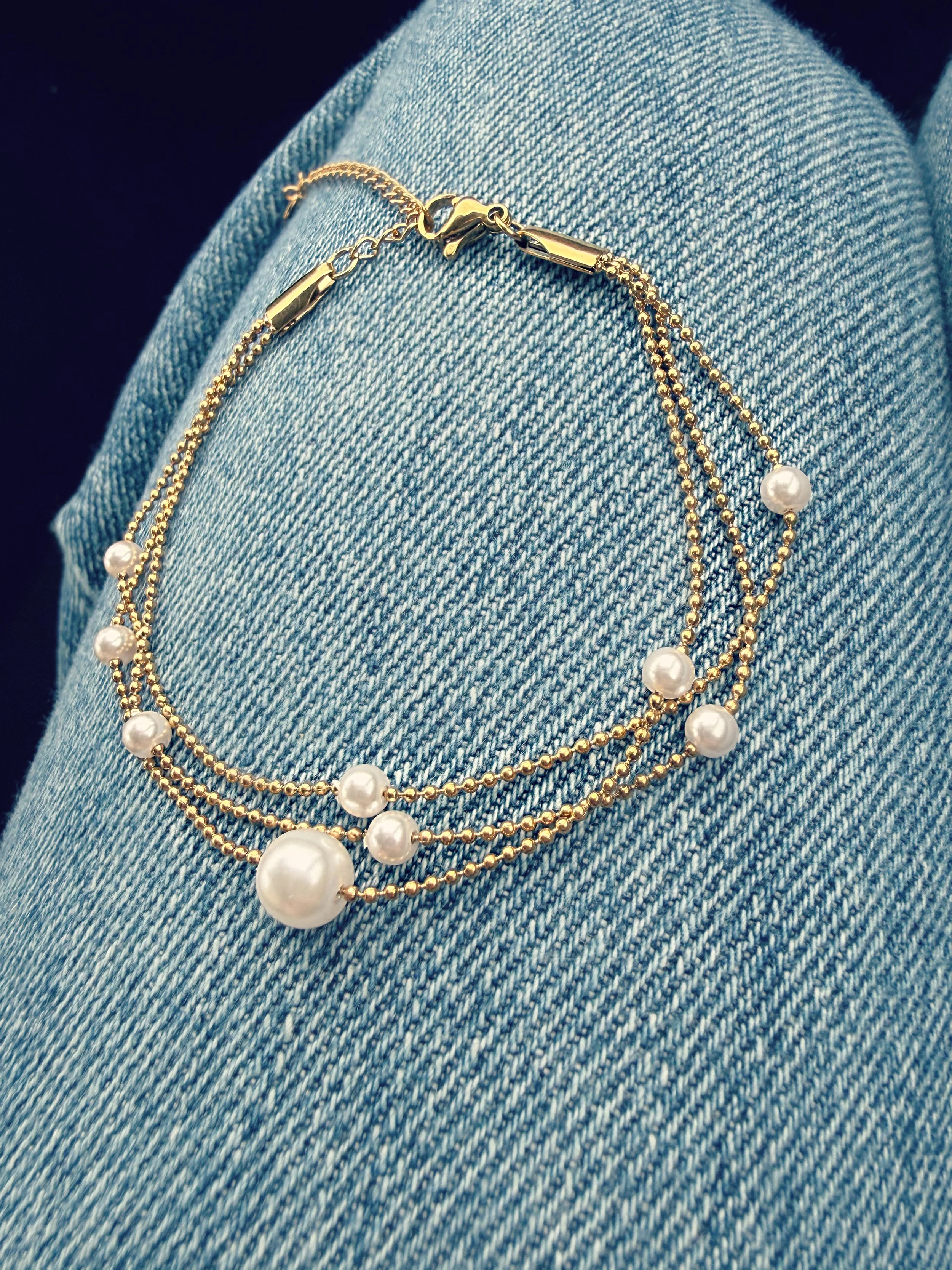 Bracelet doré multi-rangs avec perles sur fond denim-Tokade