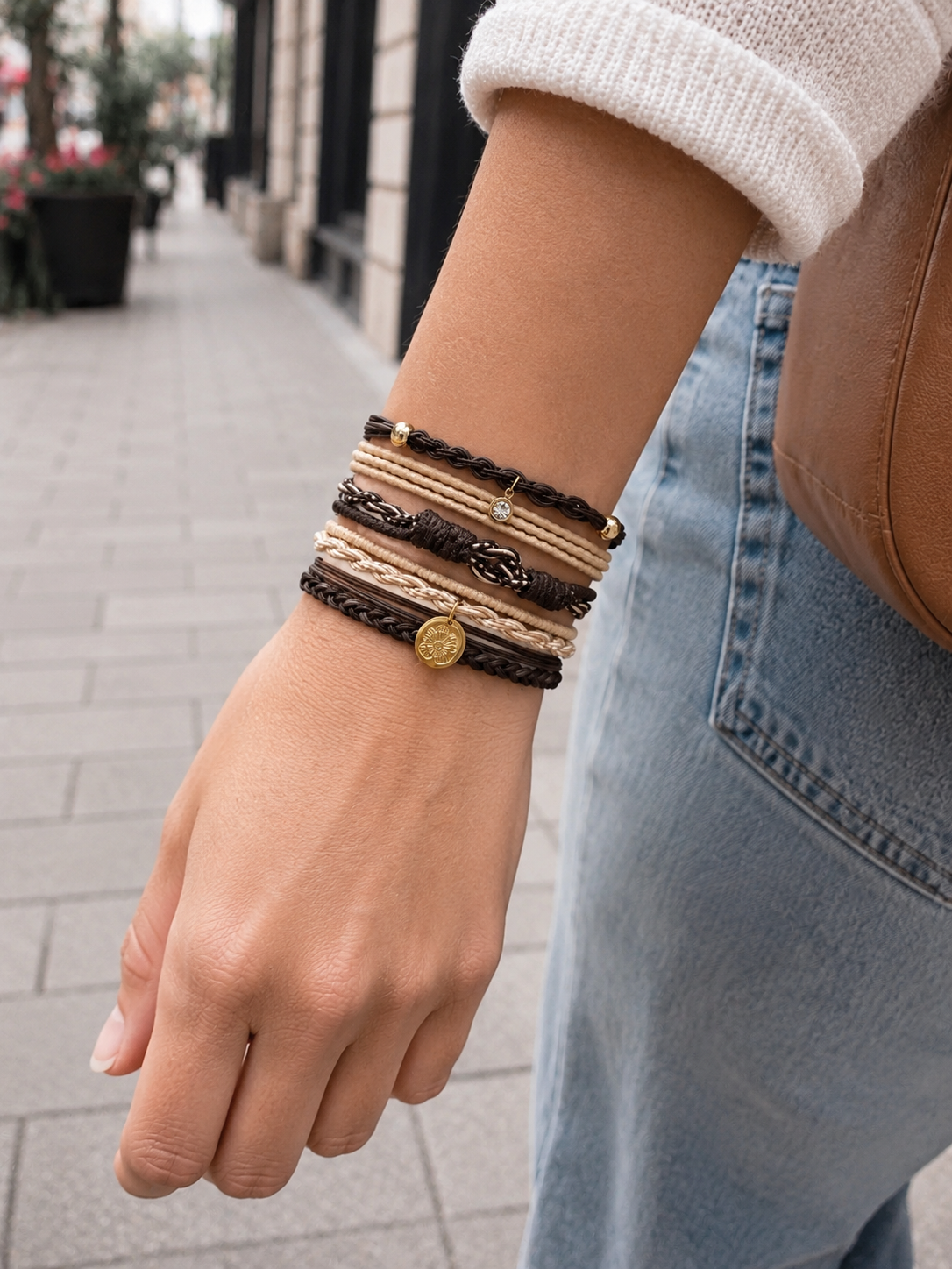 Lot de 5 élastiques à cheveux et bracelets 2-en-1 en brun, beige et doré avec tresses, cristal décoratif, médaillon gravé et cordons tressés, portés au poignet.