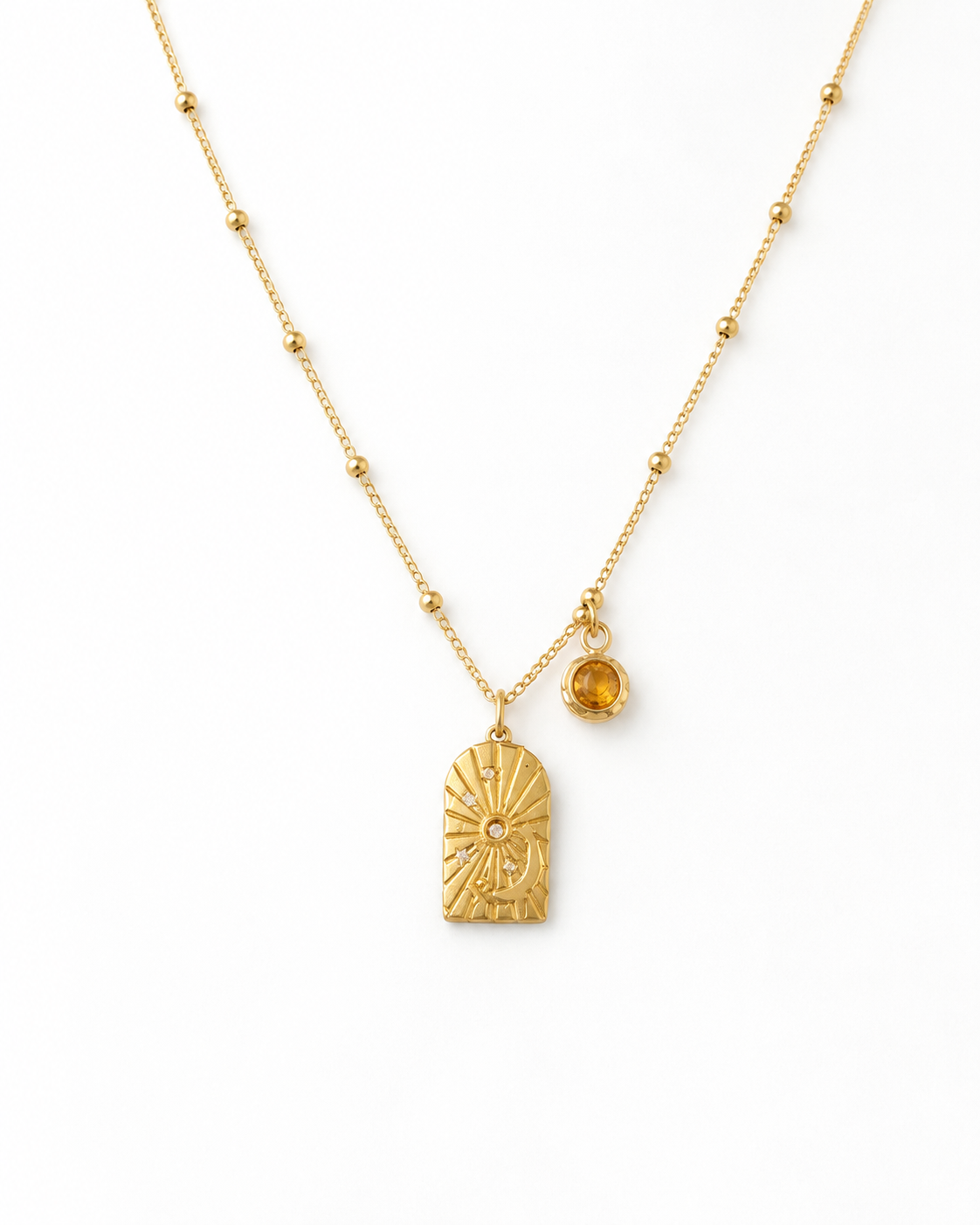 Collier Hori doré avec pendentif gravé et pierre ambrée sur fond blanc