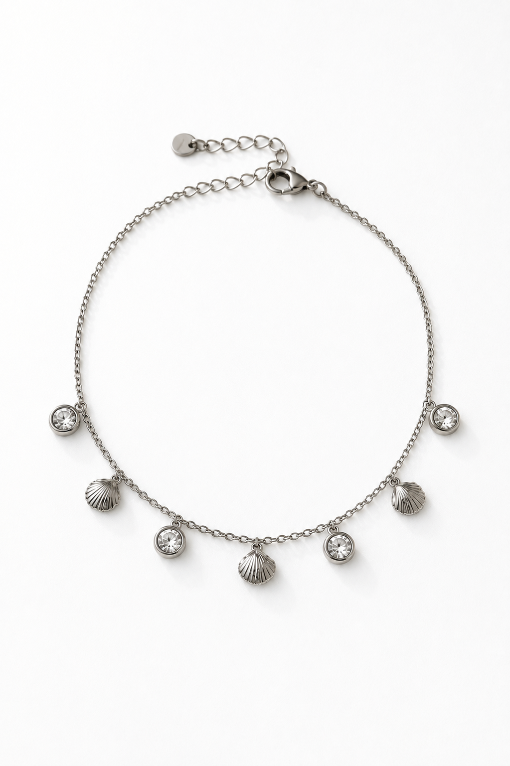 Chaîne de cheville Rina en acier inoxydable argenté avec breloques coquillages et cristaux sur fond blanc