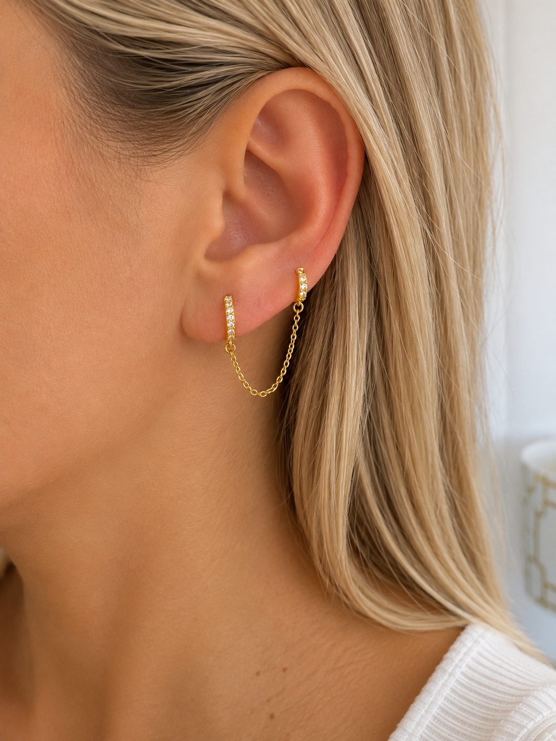 Boucles d’oreilles Tessy dorées avec chaîne et cristaux portées sur une oreille