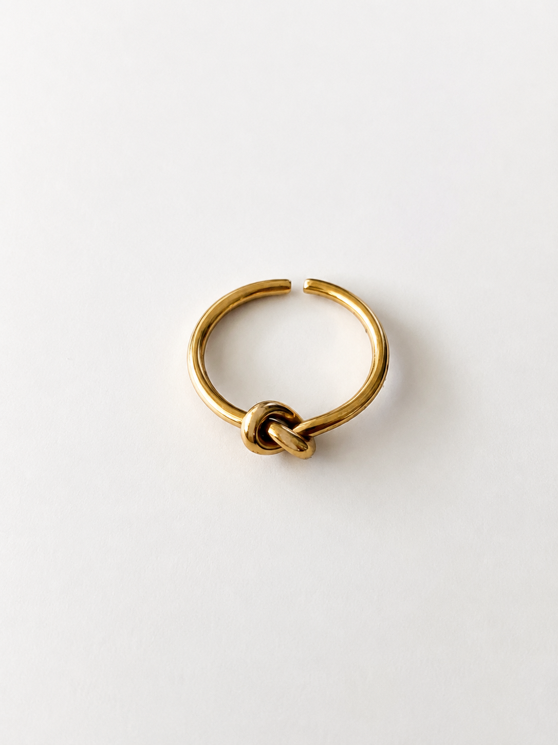 Bague June ajustable en acier inoxydable doré avec détail nœud sur fond blanc