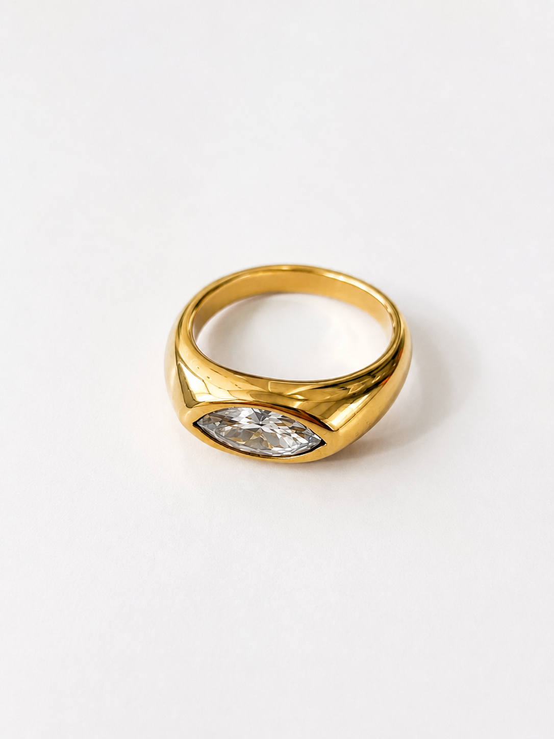 Bague Ara en acier inoxydable doré avec pierre claire taille marquise sur fond blanc