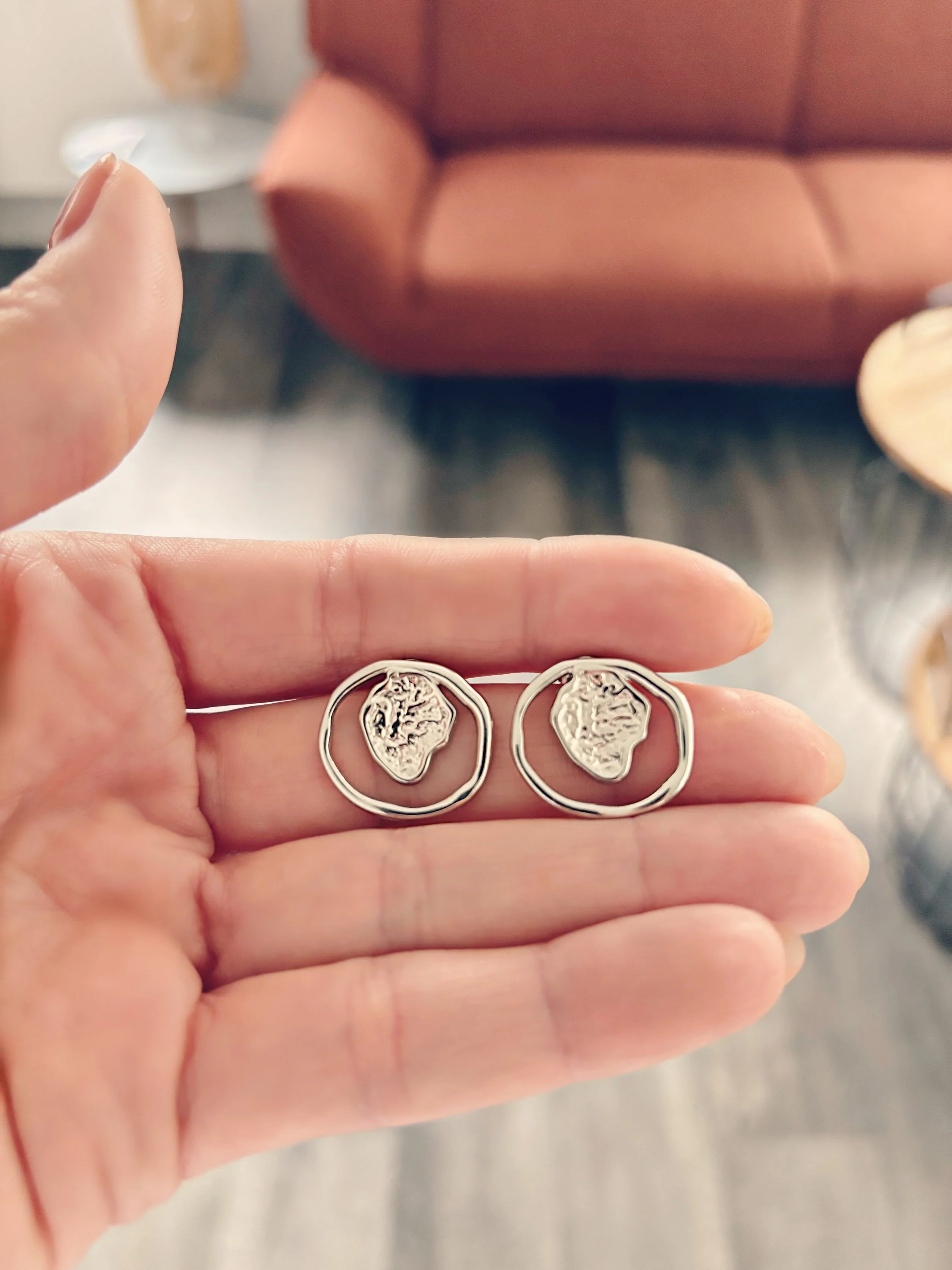 Gros plan des boucles d’oreilles Aria tenues dans la main, vue rapprochée.