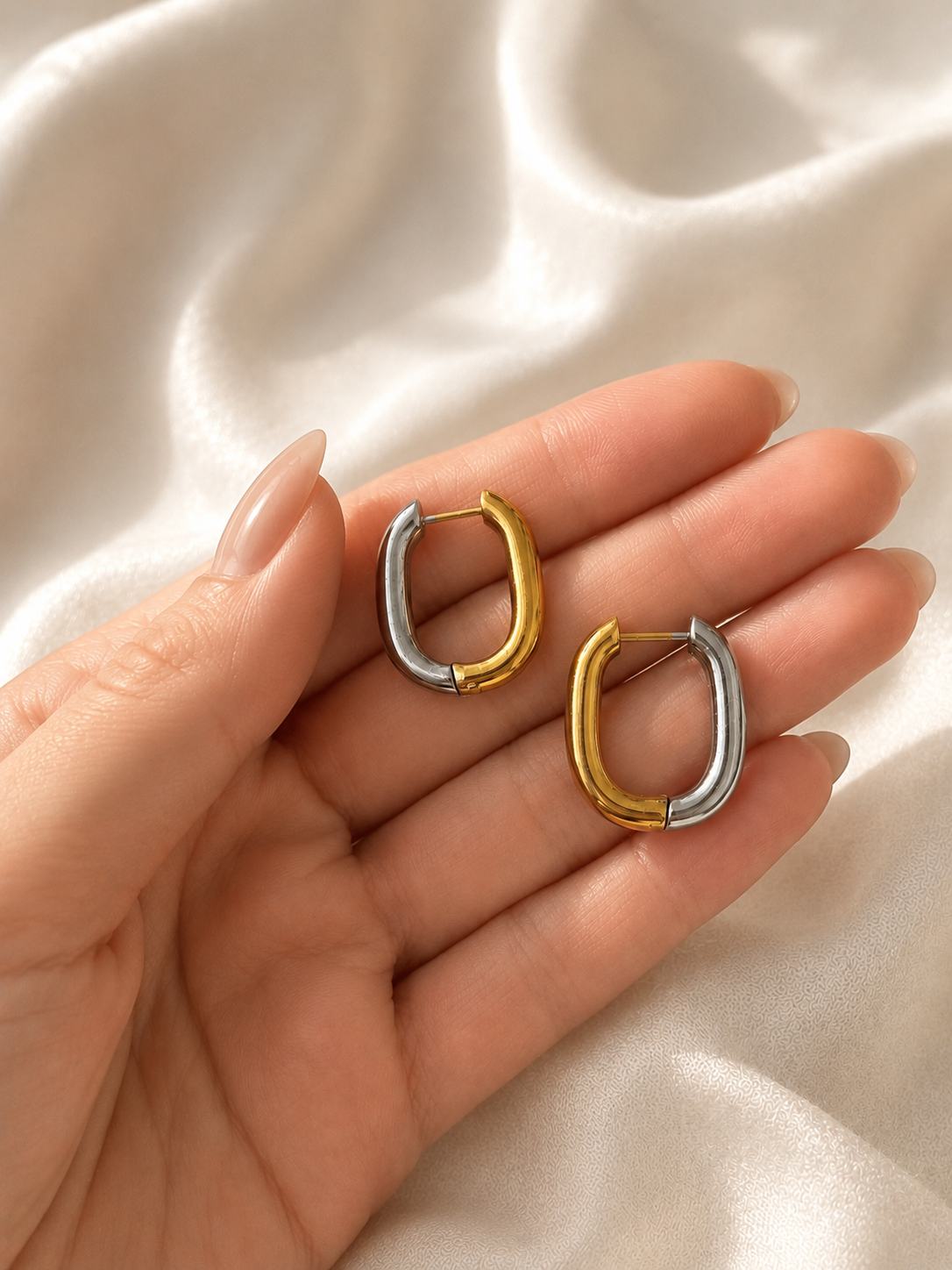 Boucles d’oreilles Daly bicolores en acier inoxydable présentées dans une main. - Tokade
