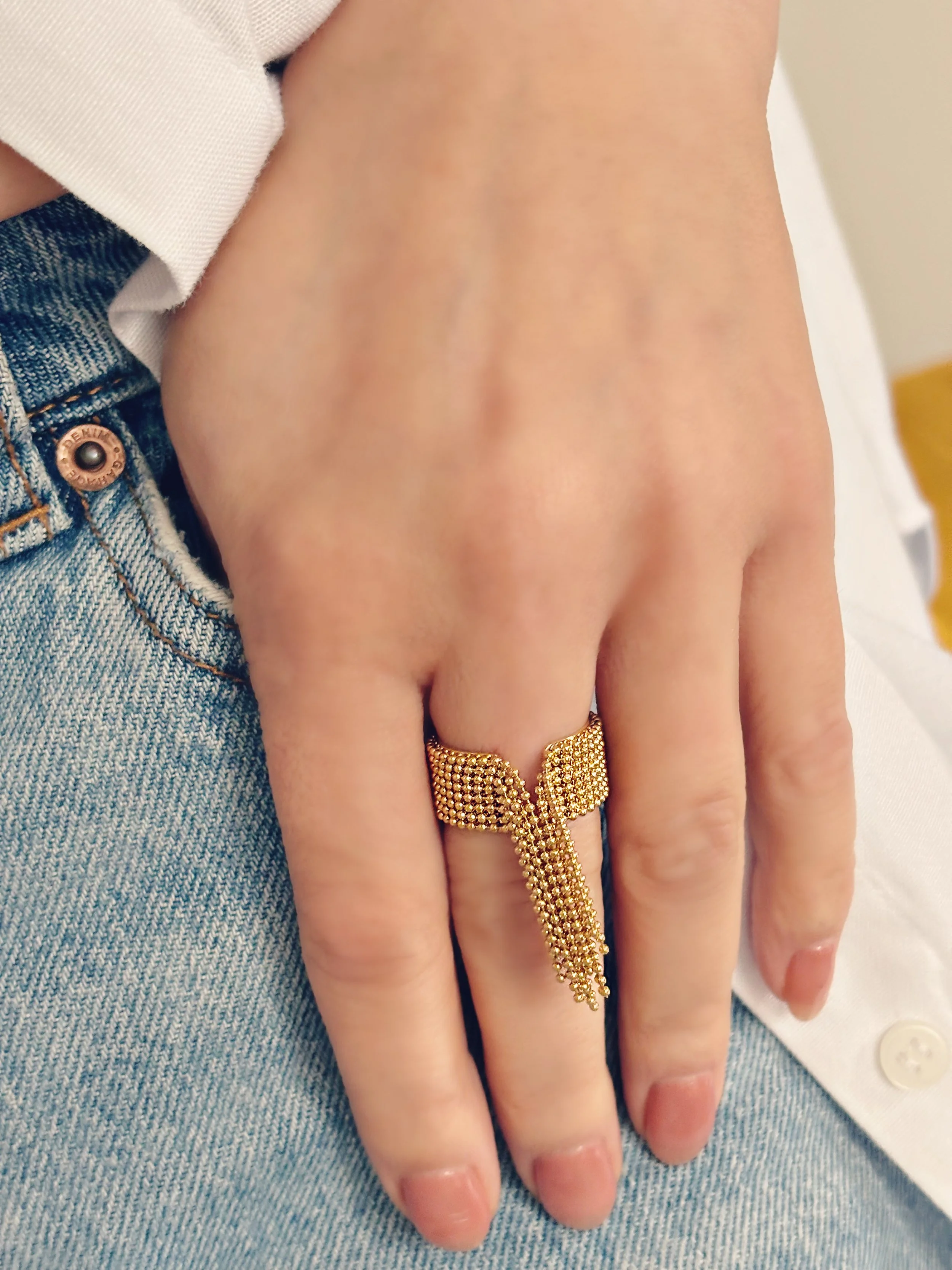 Vue rapprochée de la bague Renée, mettant en valeur les franges mobiles et la brillance de l’acier inoxydable doré.