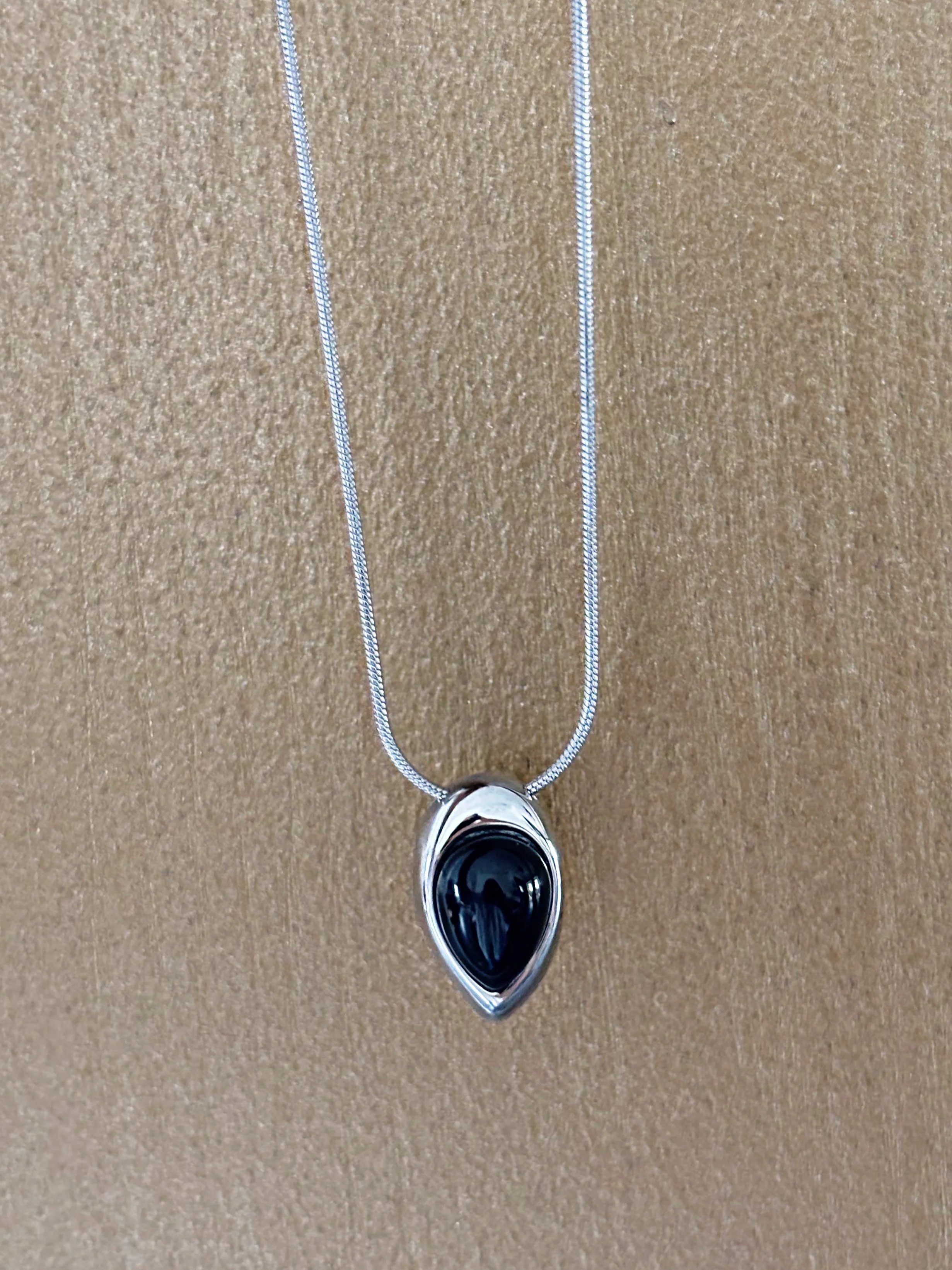 Collier présenté sur une surface neutre pour voir la chaîne dans son ensemble et le pendentif en évidence.