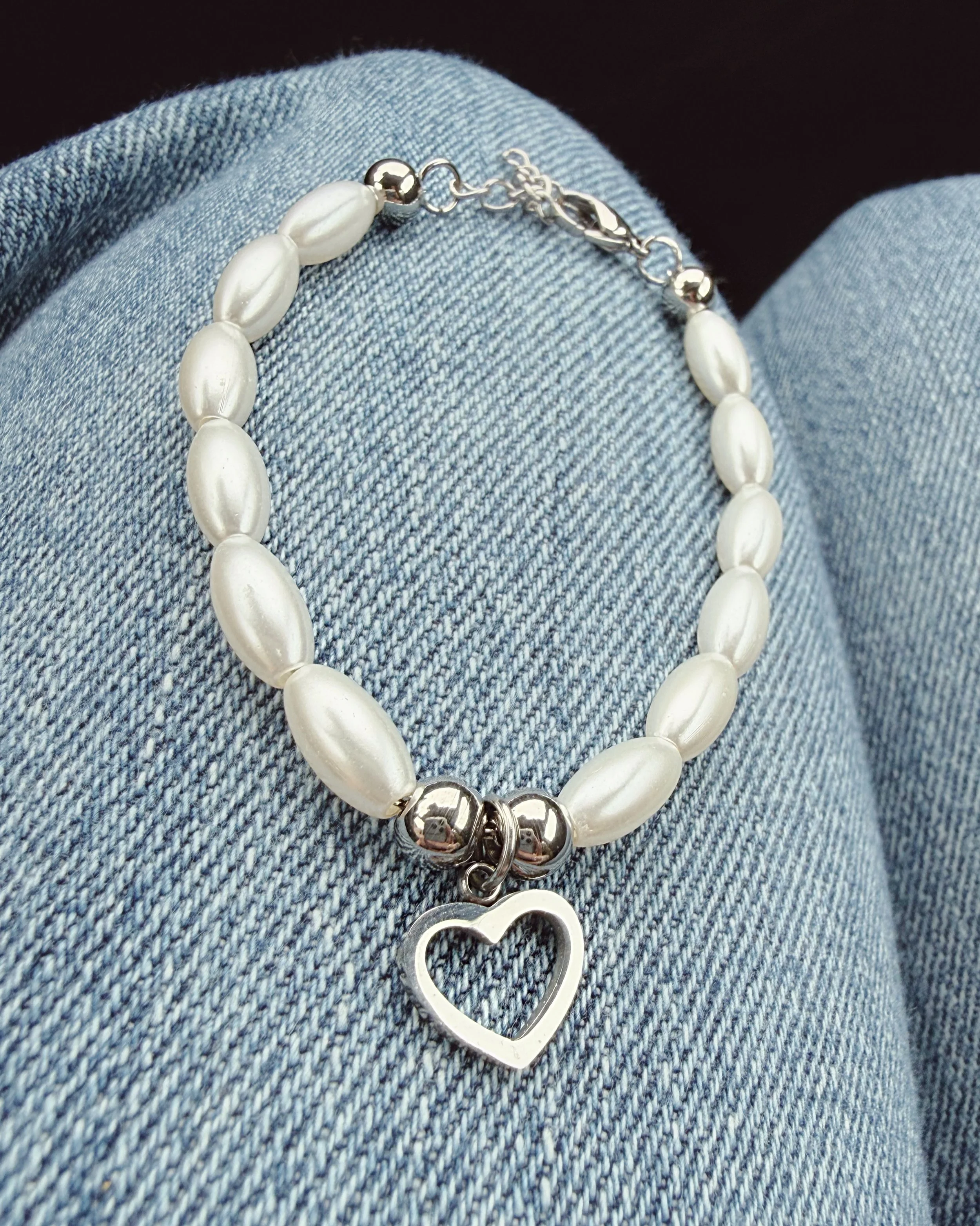 Bracelet blanc avec pendentif cœur sur fond denim