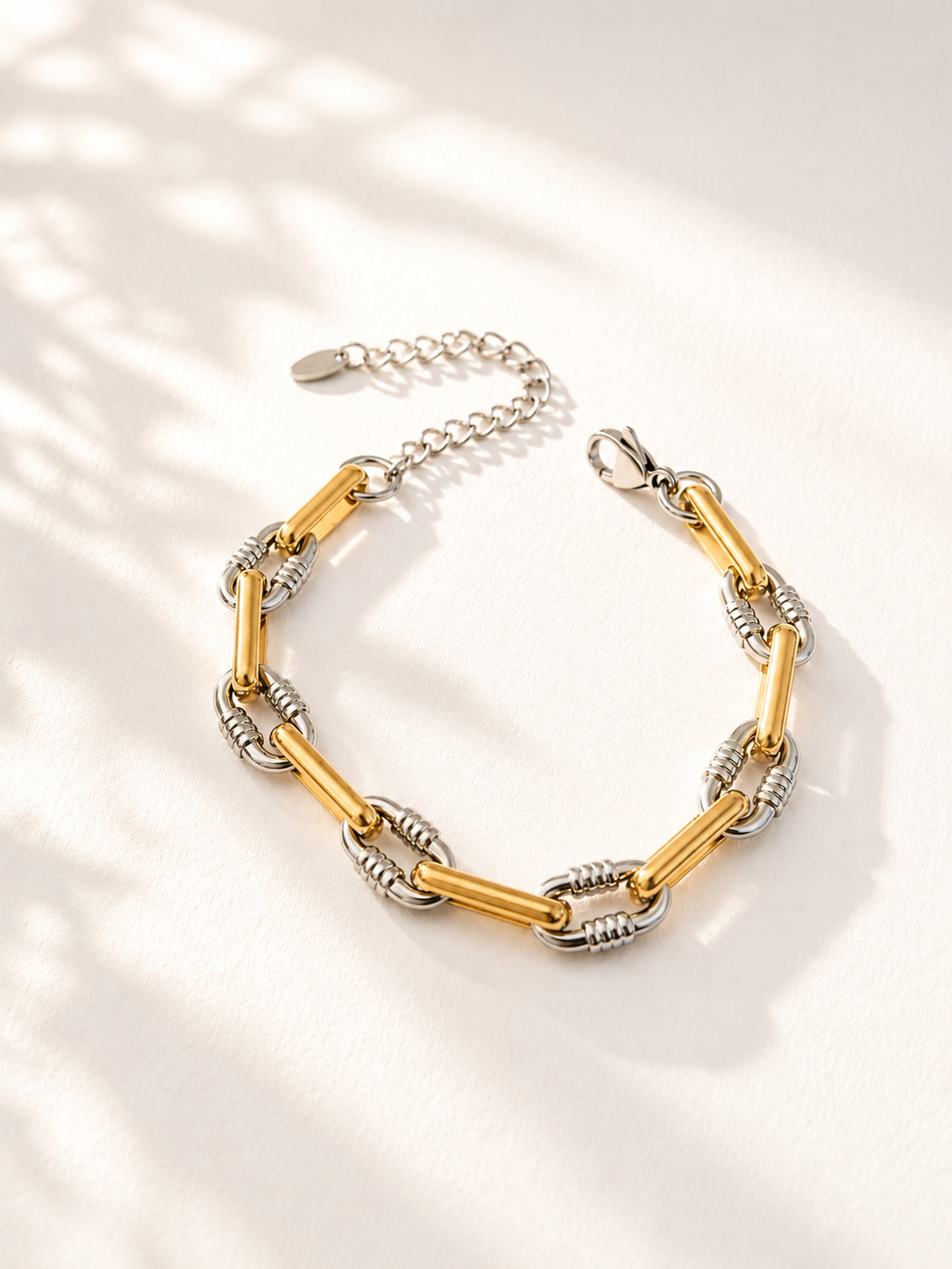 Bracelet Melba en acier inoxydable doré et argenté présenté sur un fond crème lumineux. - Tokade