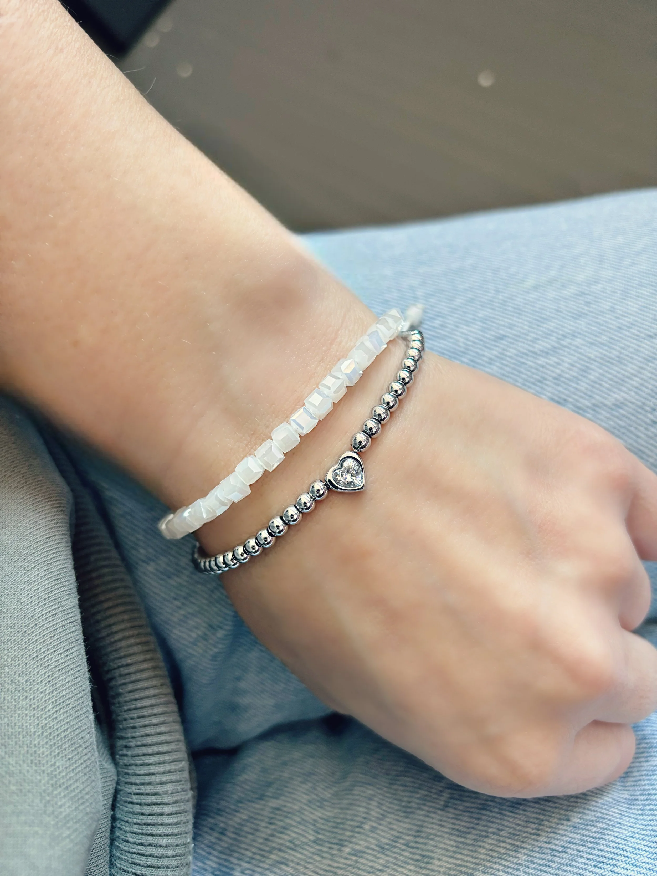 Duo de bracelets femme Tokade portés au poignet — perles blanches et cœur zircon