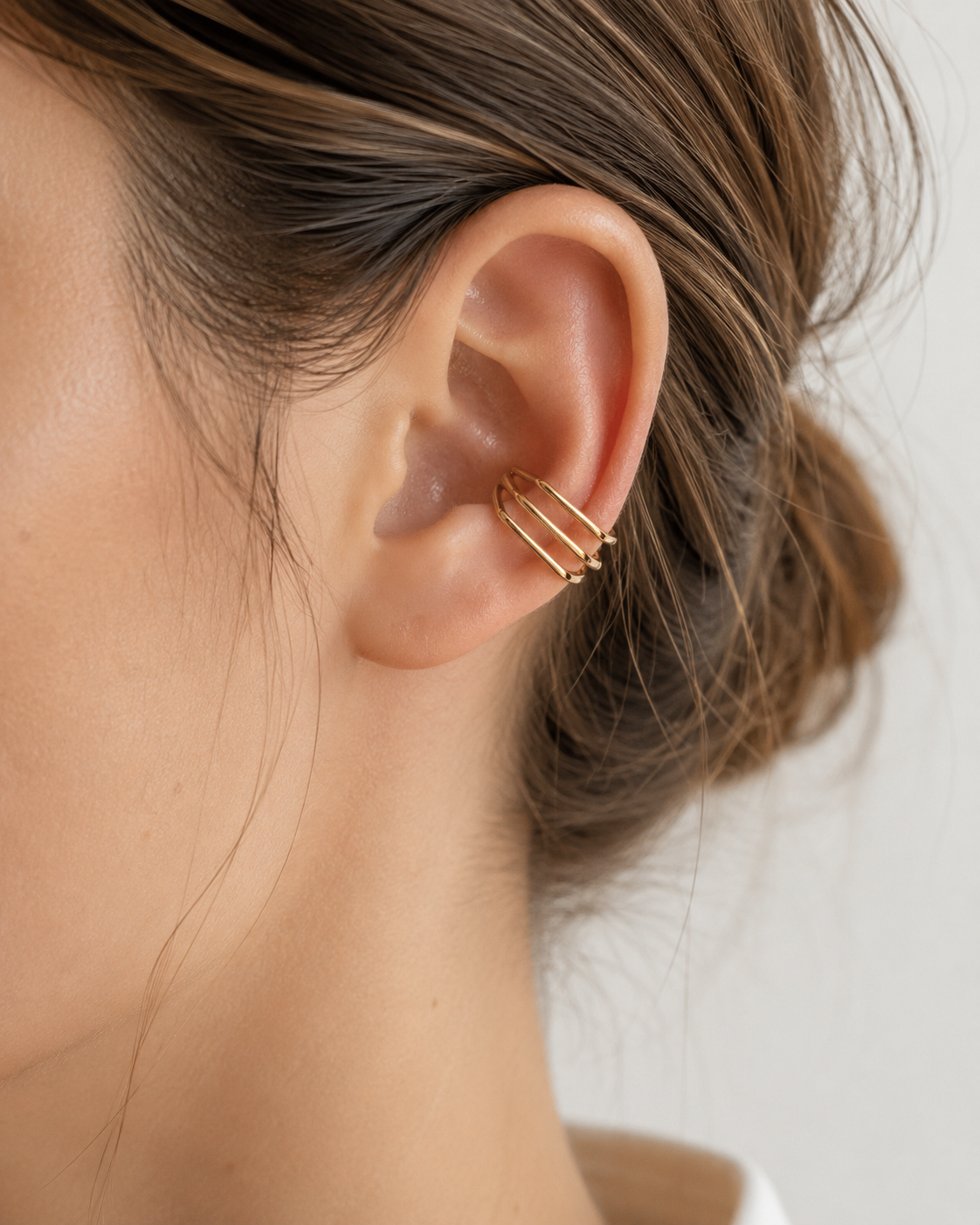 Anneau d’oreille Cassy doré porté sur l’oreille avec coiffure relevée. - Tokade