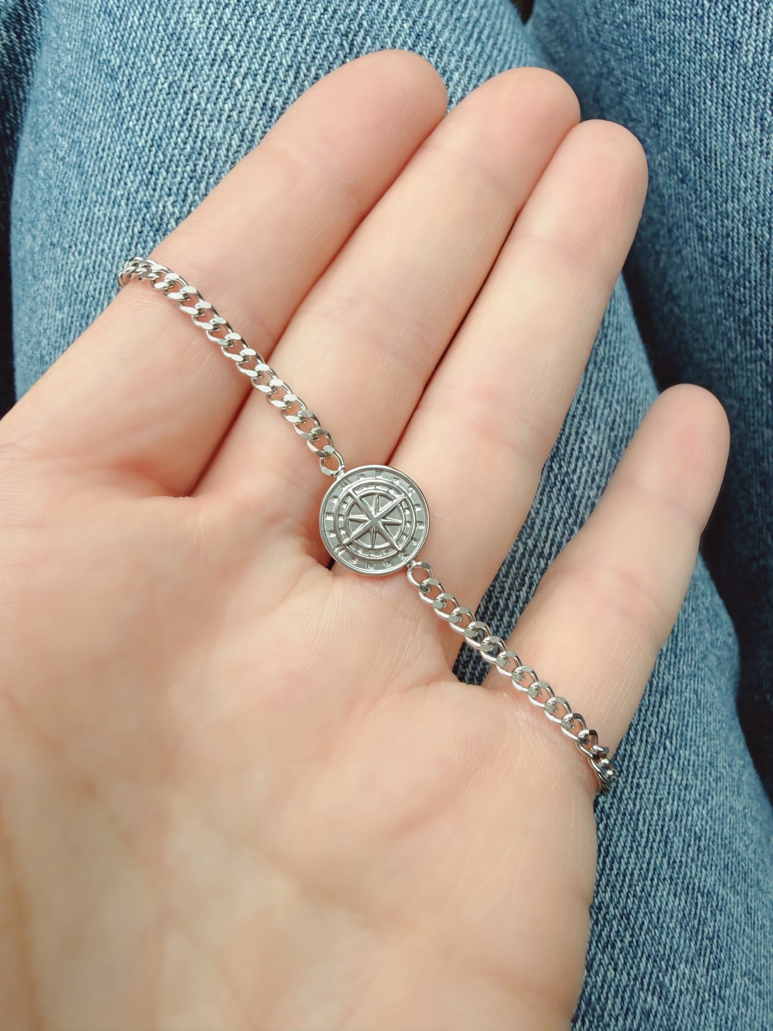 Bracelet chaîne argent avec pendentif boussole dans la main