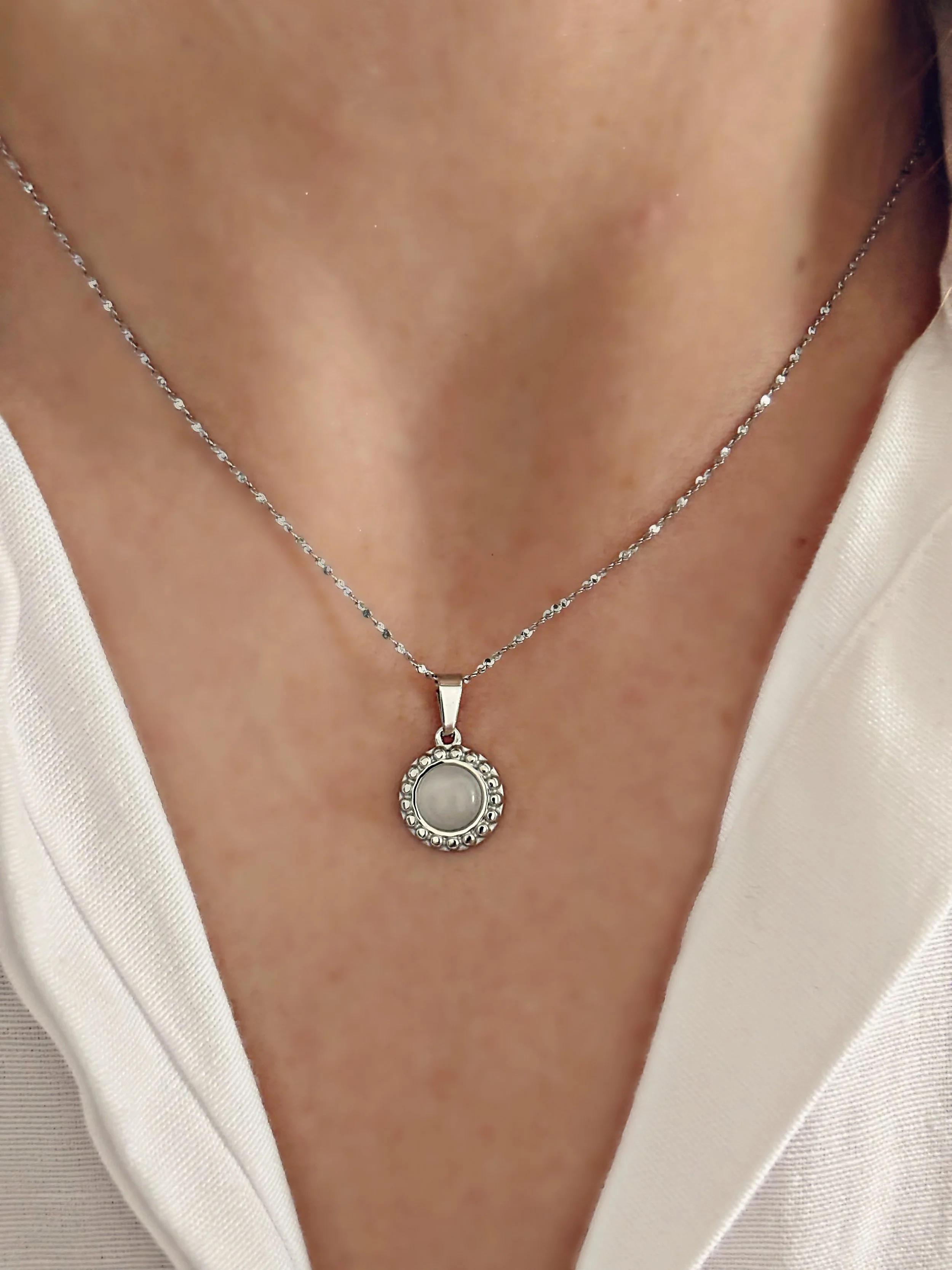 Le collier Liora porté, mettant en valeur son pendentif rond délicat au centre du décolleté.