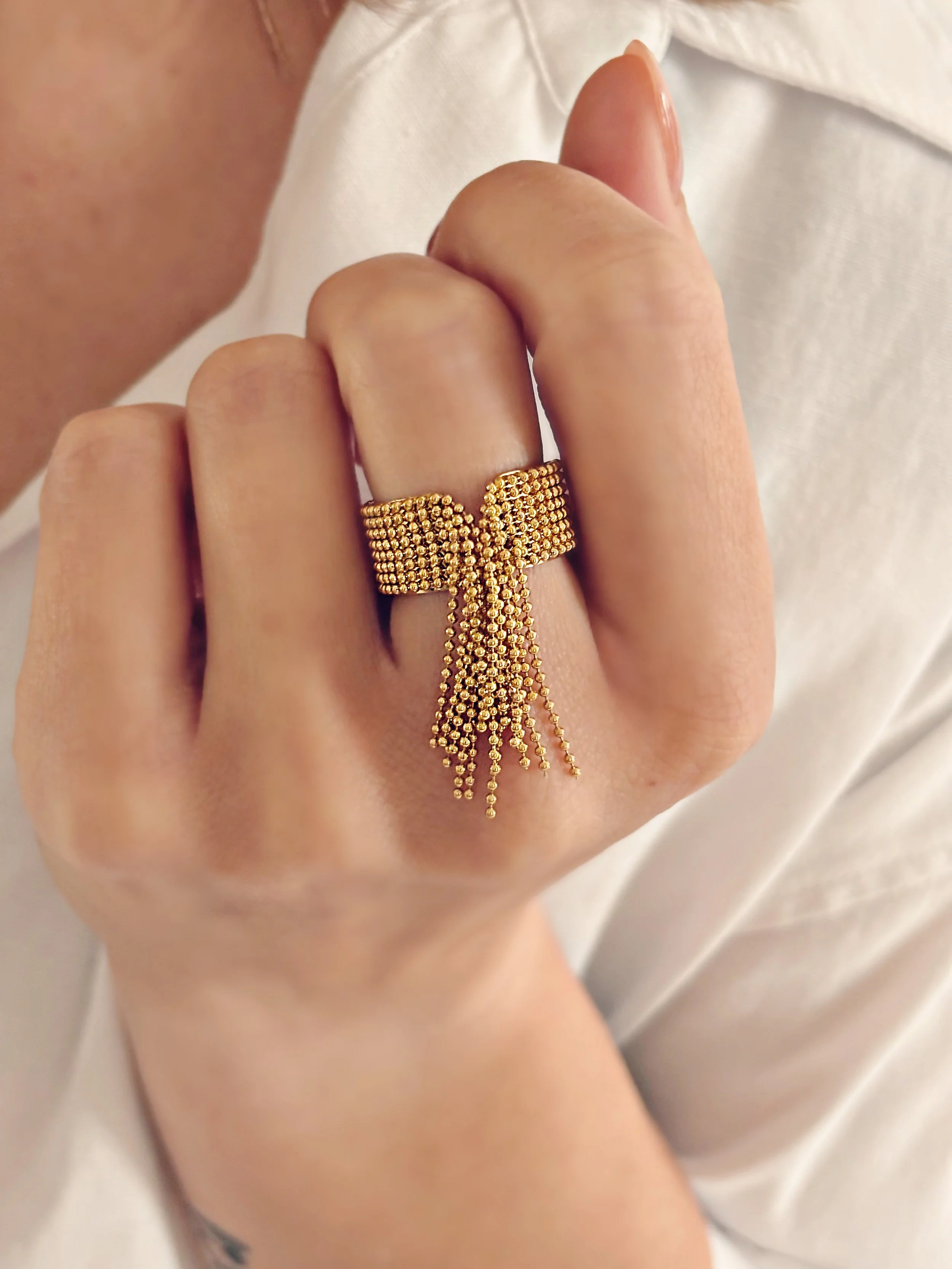 Bague Renée portée, montrant les franges dorées qui tombent délicatement sur la main.
