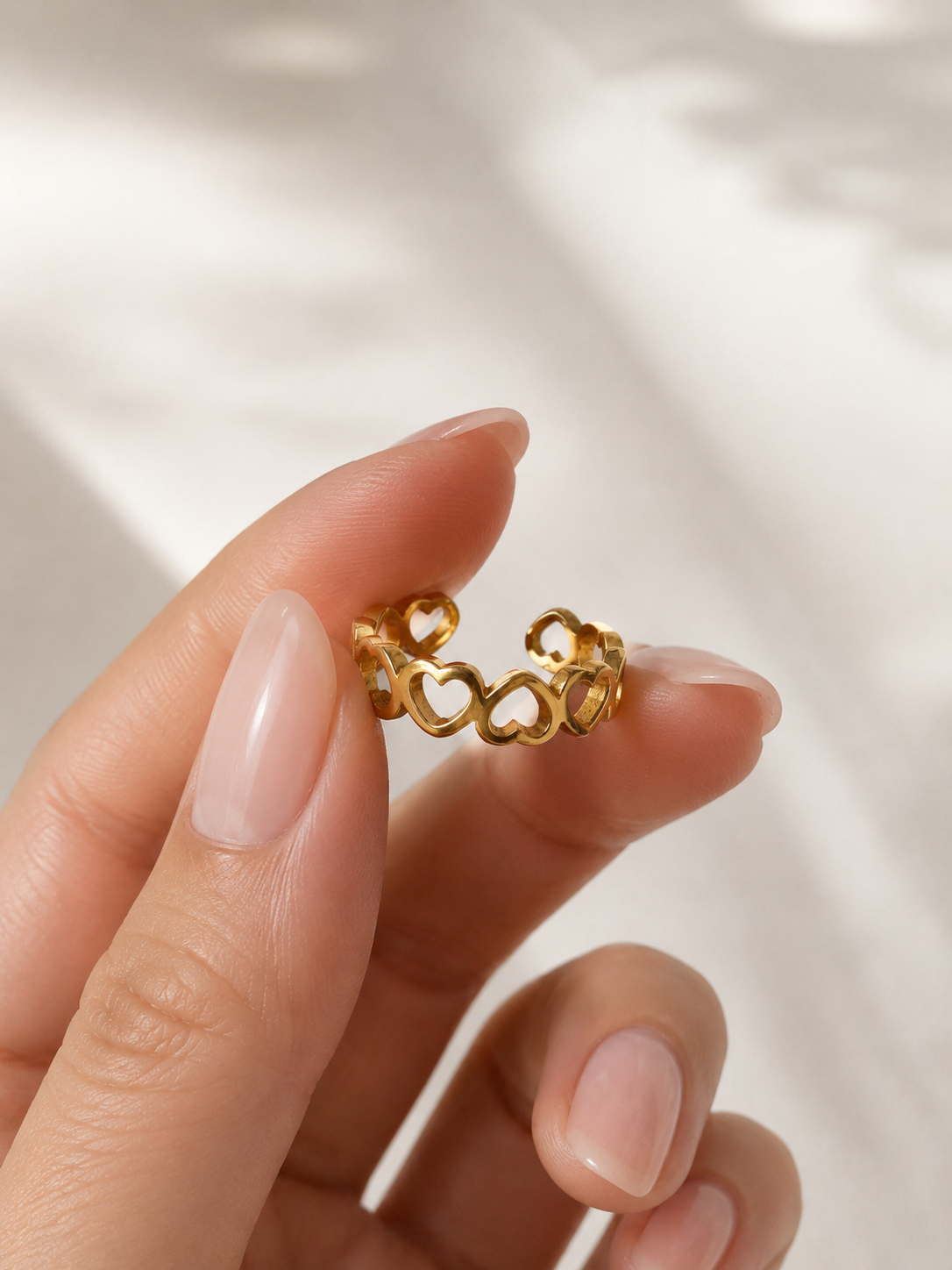 Bague d’orteil Gina en acier inoxydable doré avec rangée de petits cœurs ajourés ajustable. Par Tokade