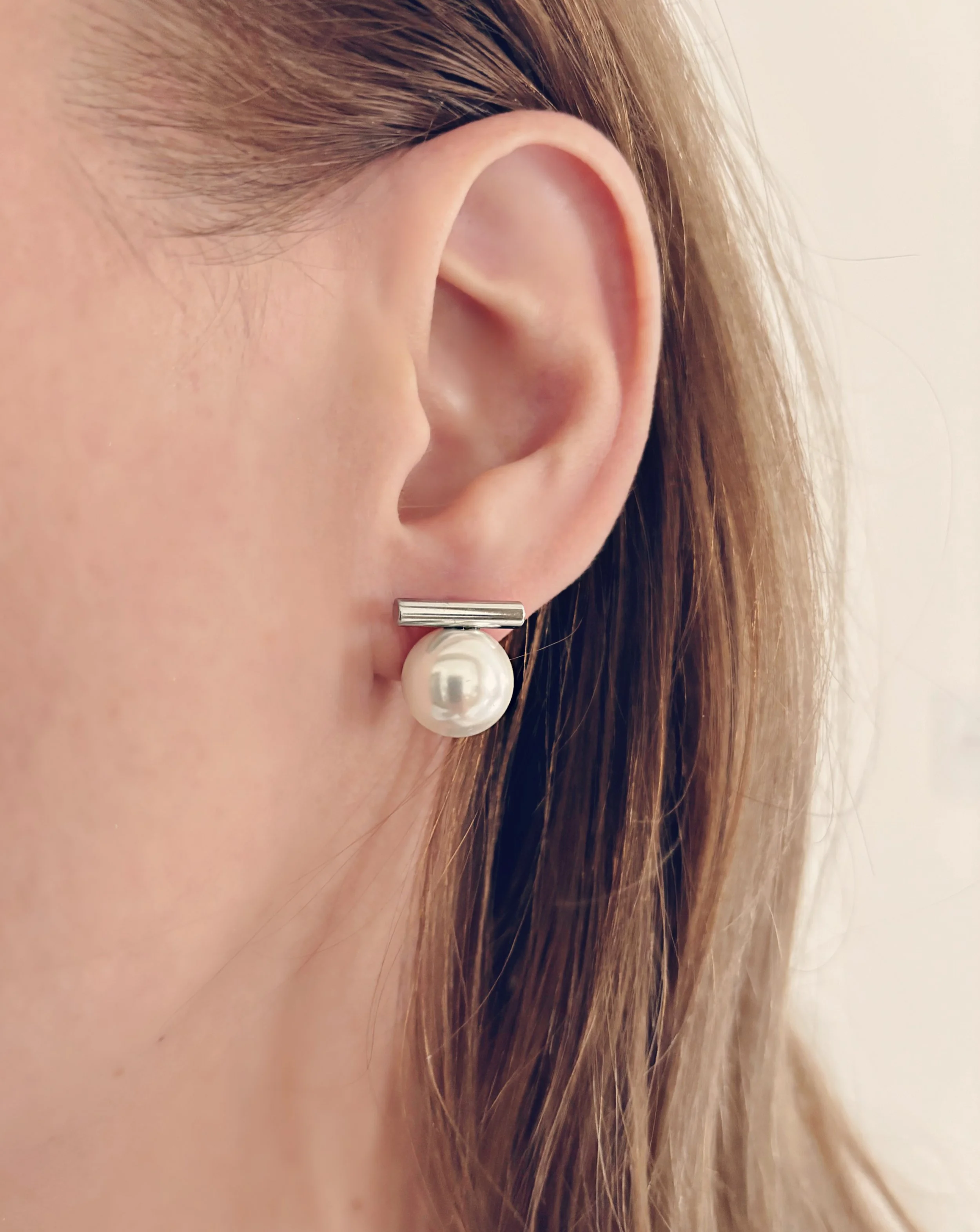 Boucles d’oreilles Alicia portées, mettant en valeur la perle et la barre en acier inoxydable.