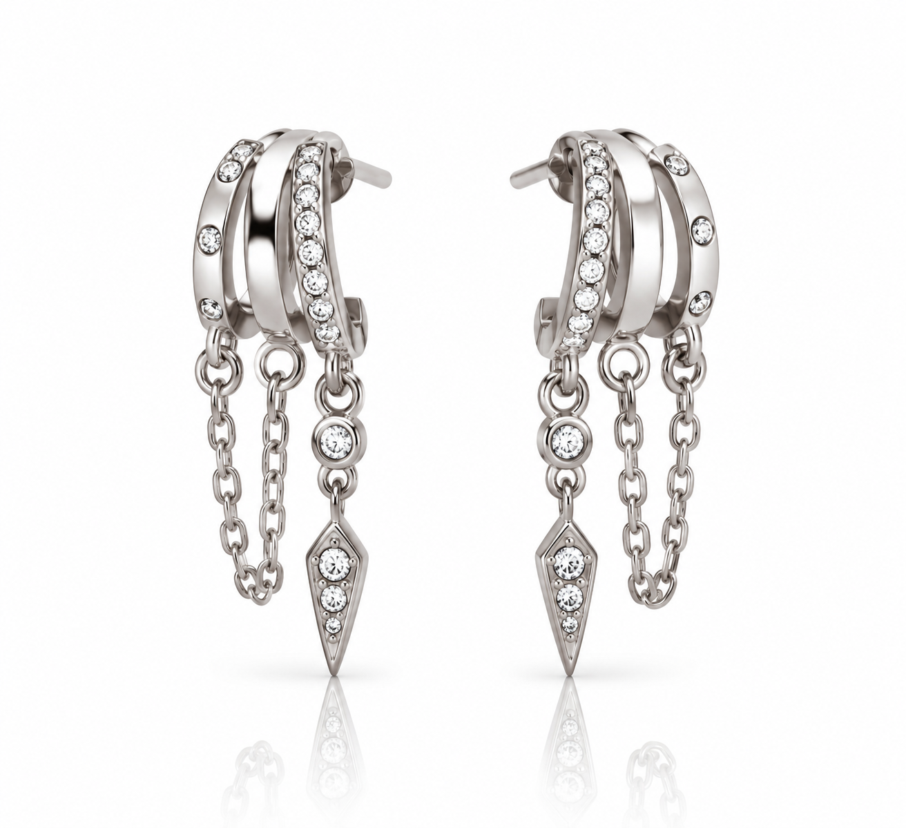 Paire de boucles d’oreilles Jenna avec trois anneaux, pierres scintillantes, chaînettes et breloques pointues sur fond blanc.