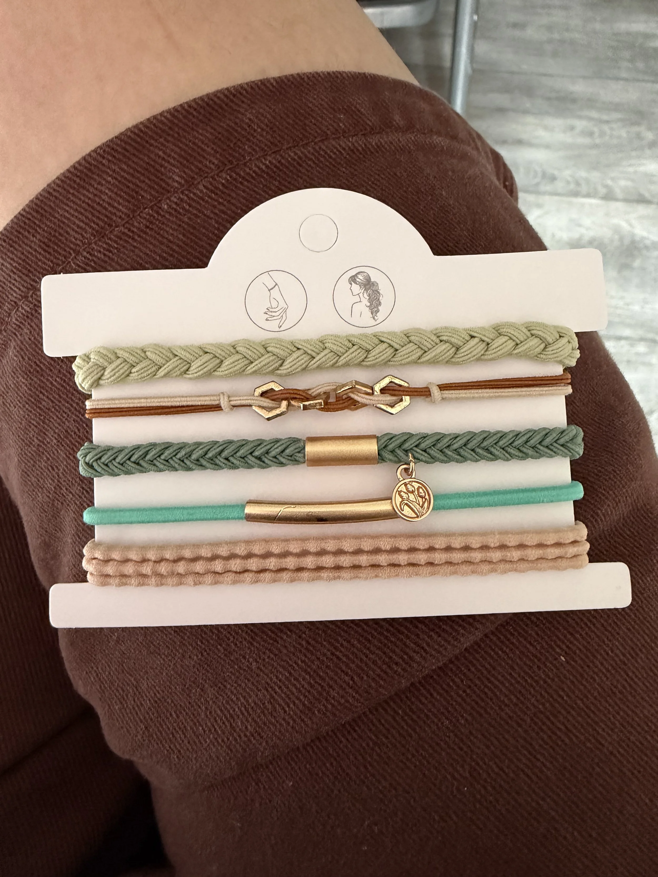 Lot de 5 élastiques à cheveux et bracelets 2-en-1 vert sauge, beige et turquoise avec maillons décoratifs, médaillon gravé et détails dorés.