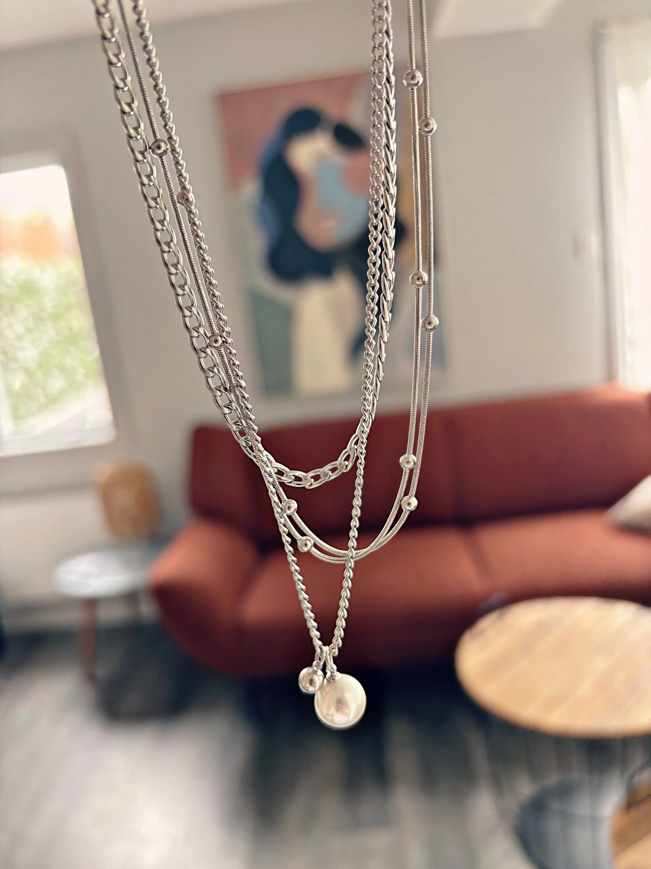 Vue rapprochée du collier suspendu, montrant les détails des chaînes et des perles.