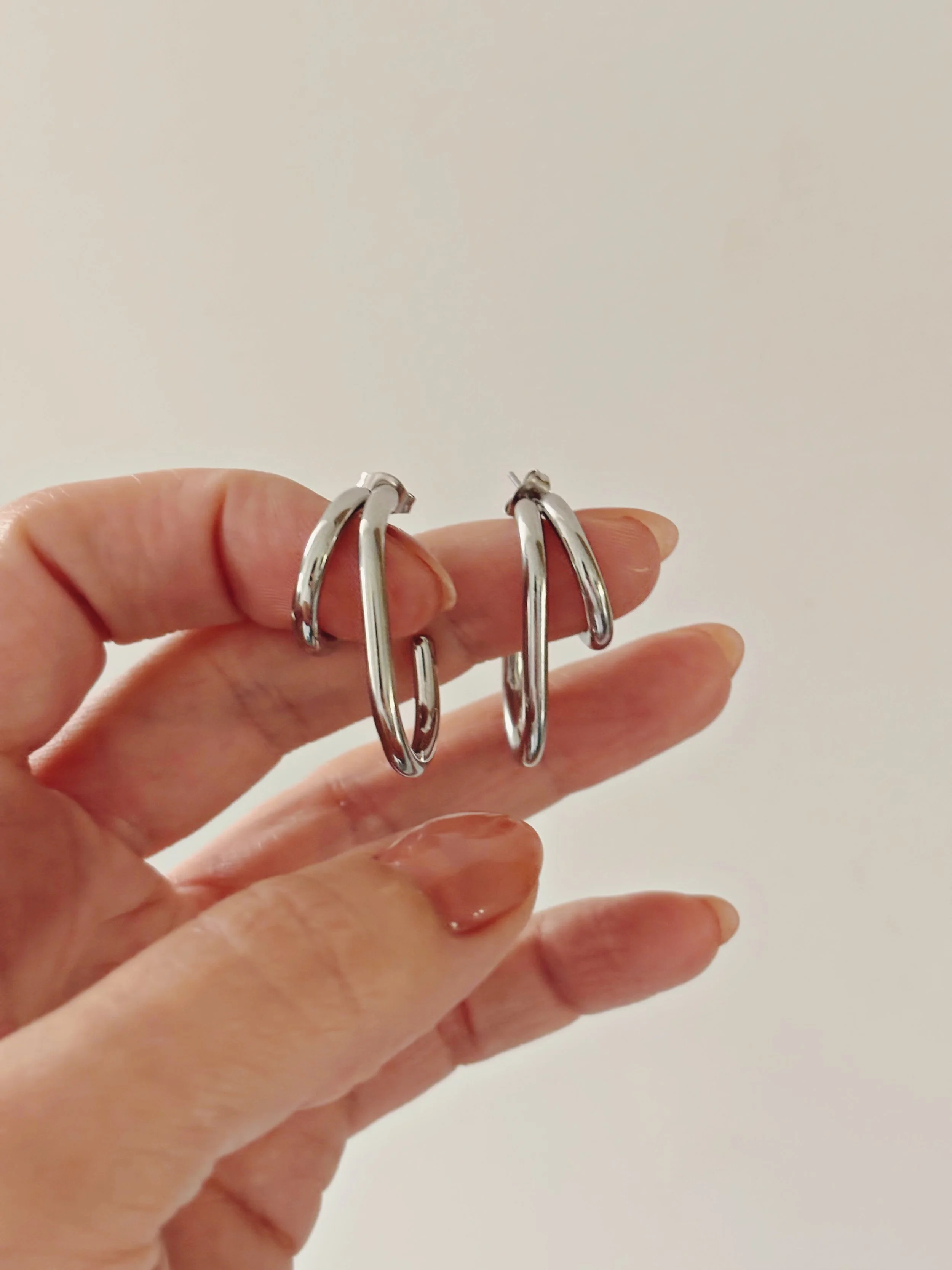 Boucles Zoé tenues dans la main, mettant en valeur leur forme unique.