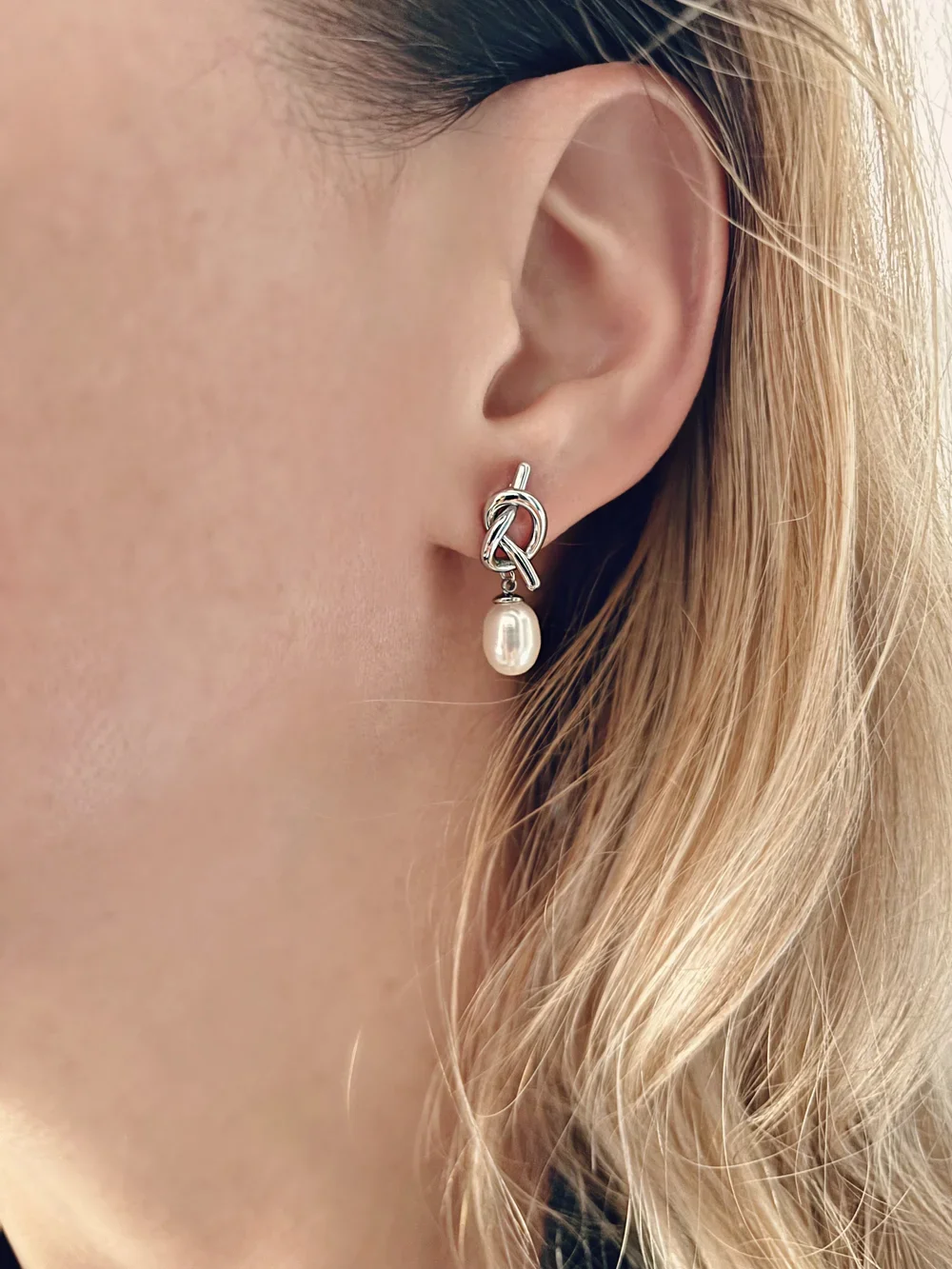Boucles d’oreilles Selya en acier inoxydable argenté avec perle blanche, portées à l’oreille – bijou élégant et durable signé Tokade.