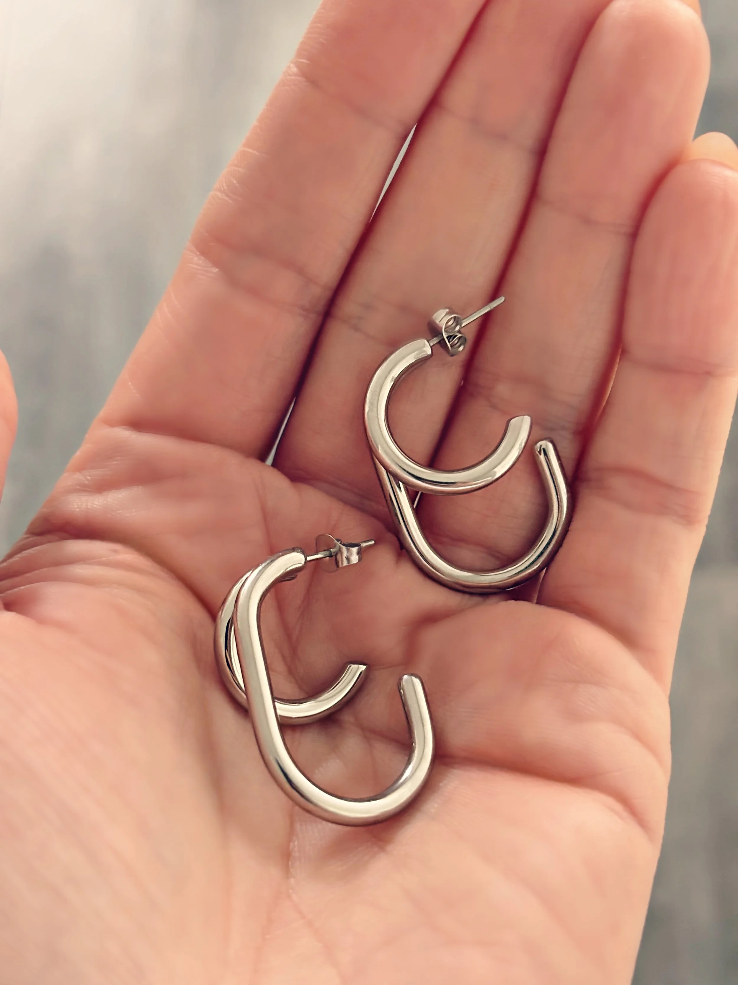 Boucles Zoé posées dans la main, vue rapprochée sur leur design double.