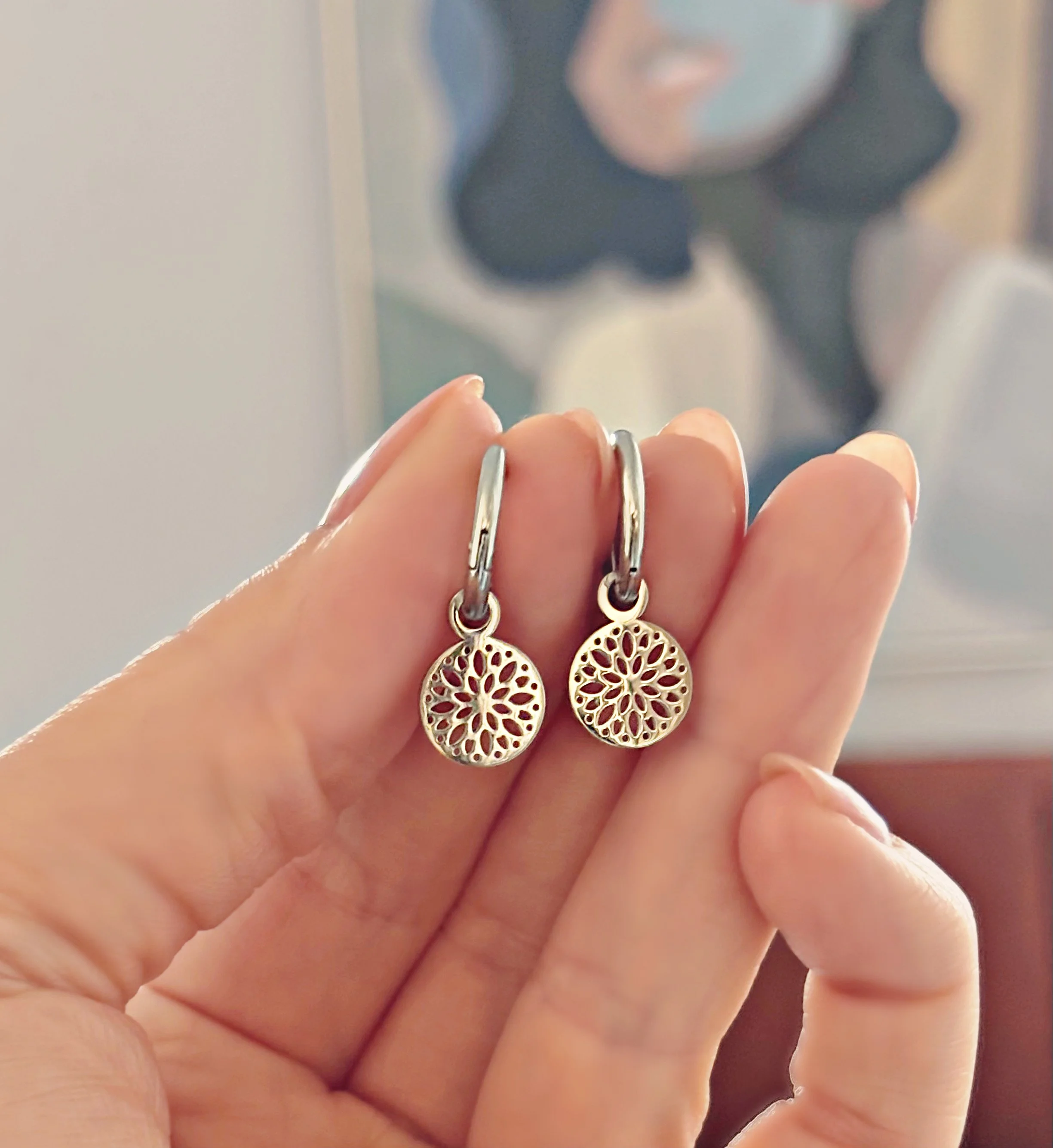Gros plan des boucles d’oreilles Solia suspendues, motif floral visible.