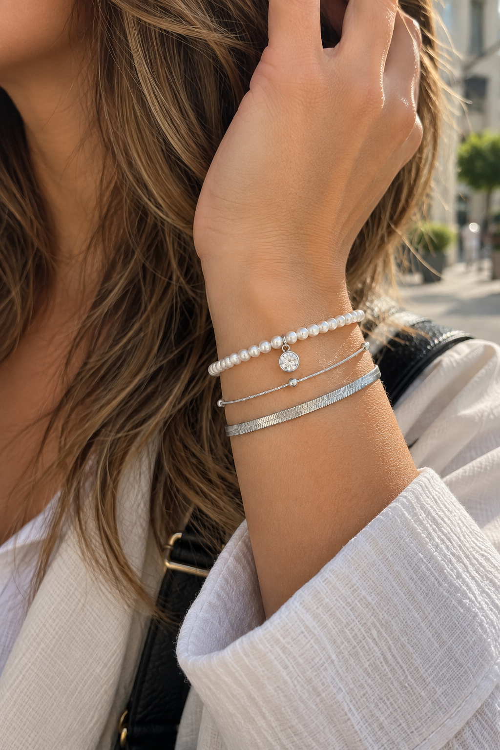 Bracelet Tamia trois rangs argenté avec perles et breloque brillante porté au poignet