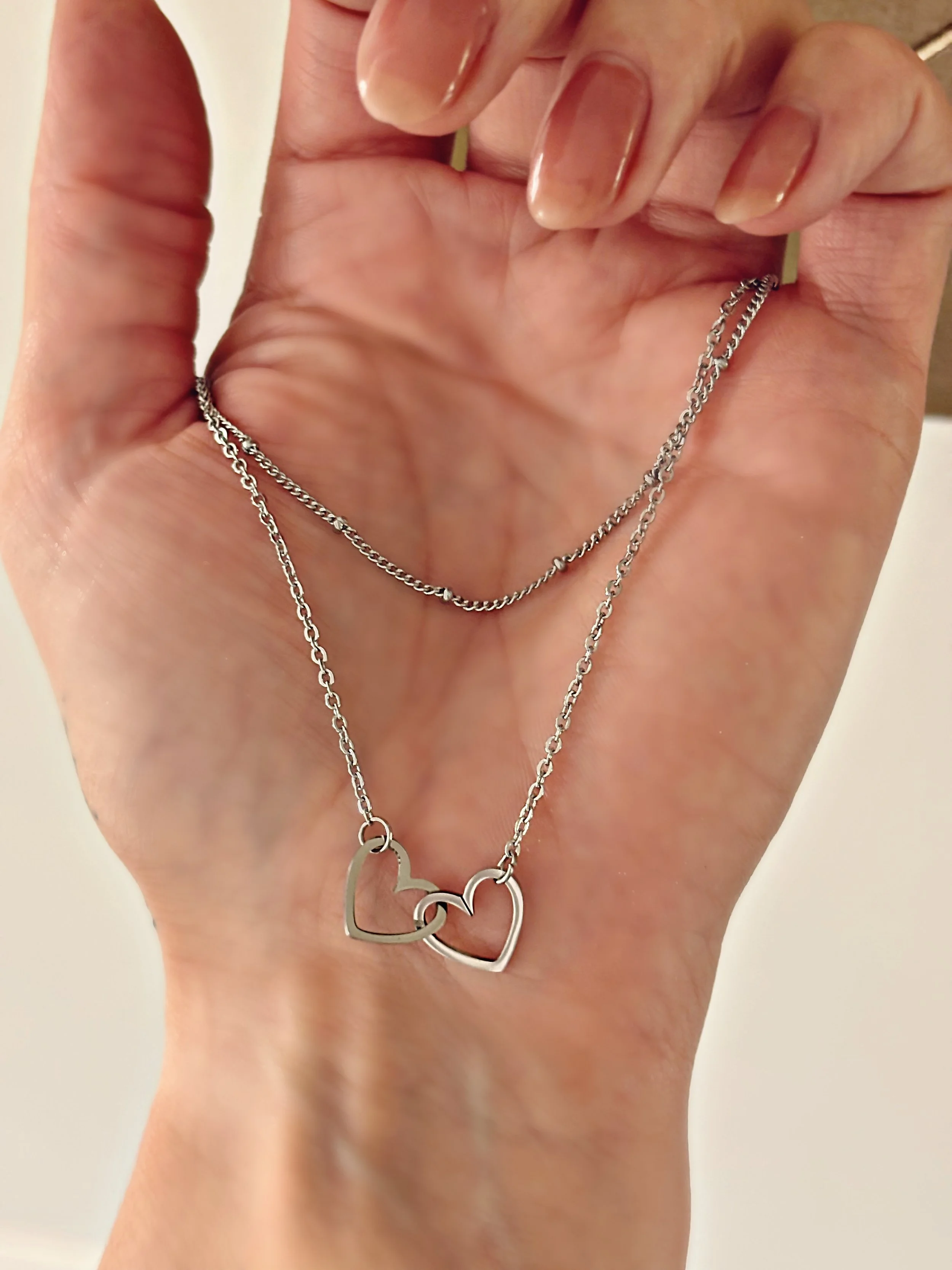 Collier Kalia tenu dans la main, illustrant la finesse des chaînes et la brillance de l’acier inoxydable.