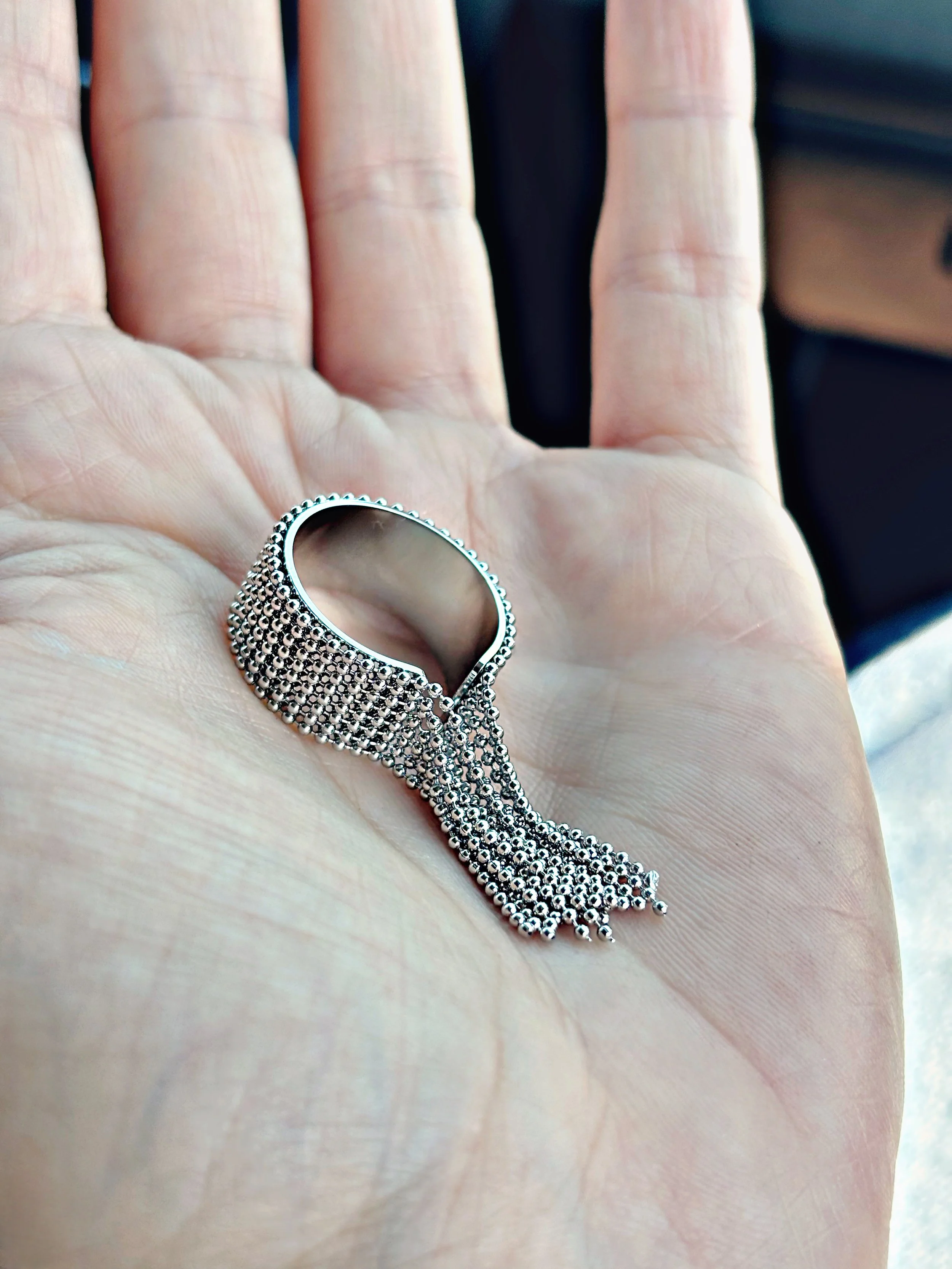 Bague en acier inoxydable argentée avec franges de chaînes, bijou original et tendance porté au doigt.