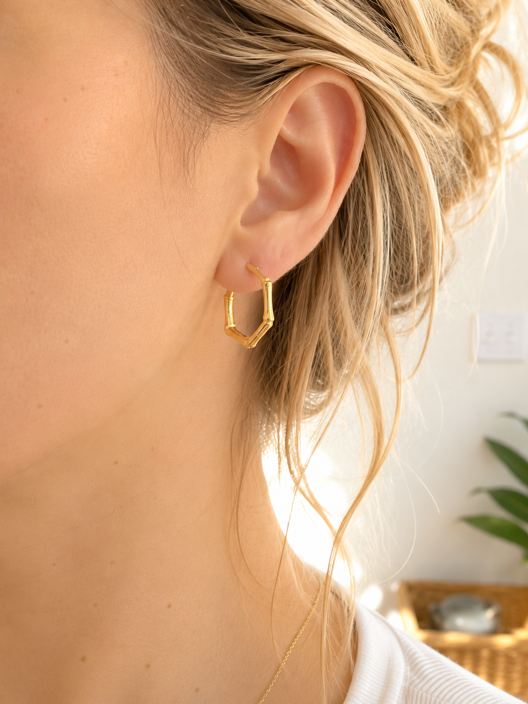 Femme portant les boucles d’oreilles Viky en acier inoxydable doré au design inspiré du bambou.