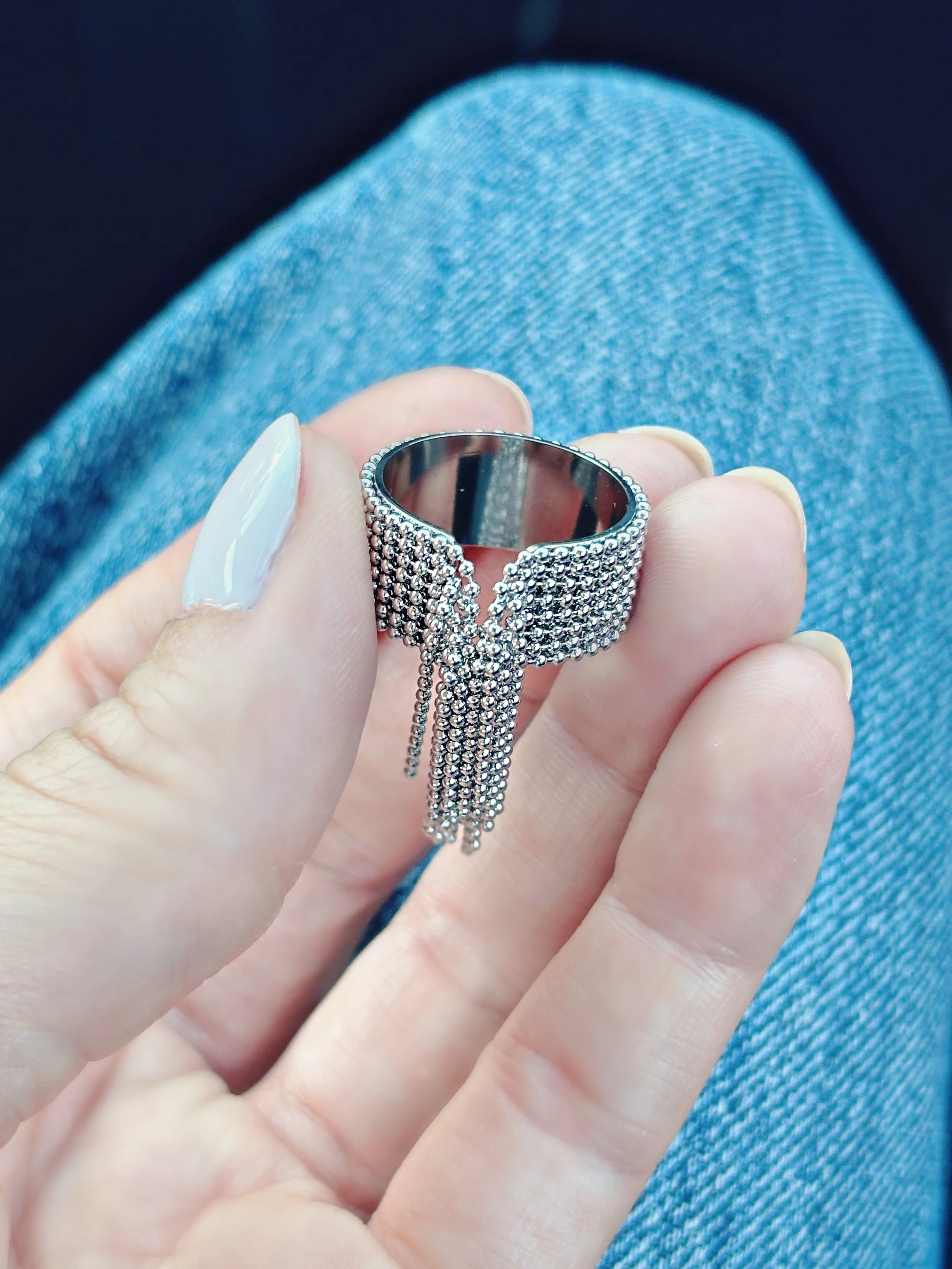 Bague en acier inoxydable argentée avec franges de chaînes, bijou original et tendance porté au doigt.