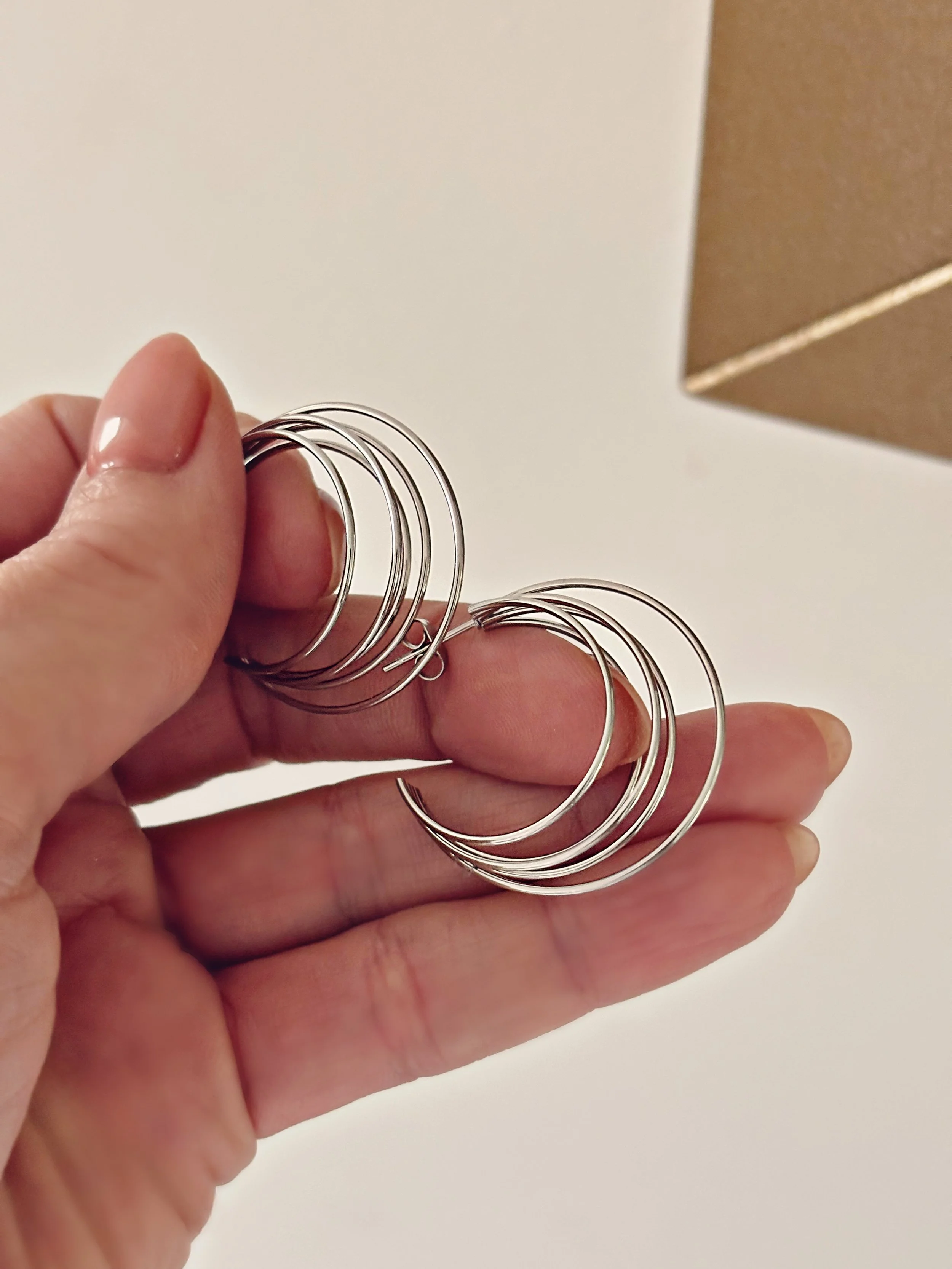Gros plan des boucles Ellia dans la main, vue rapprochée sur leur design fin et moderne.
