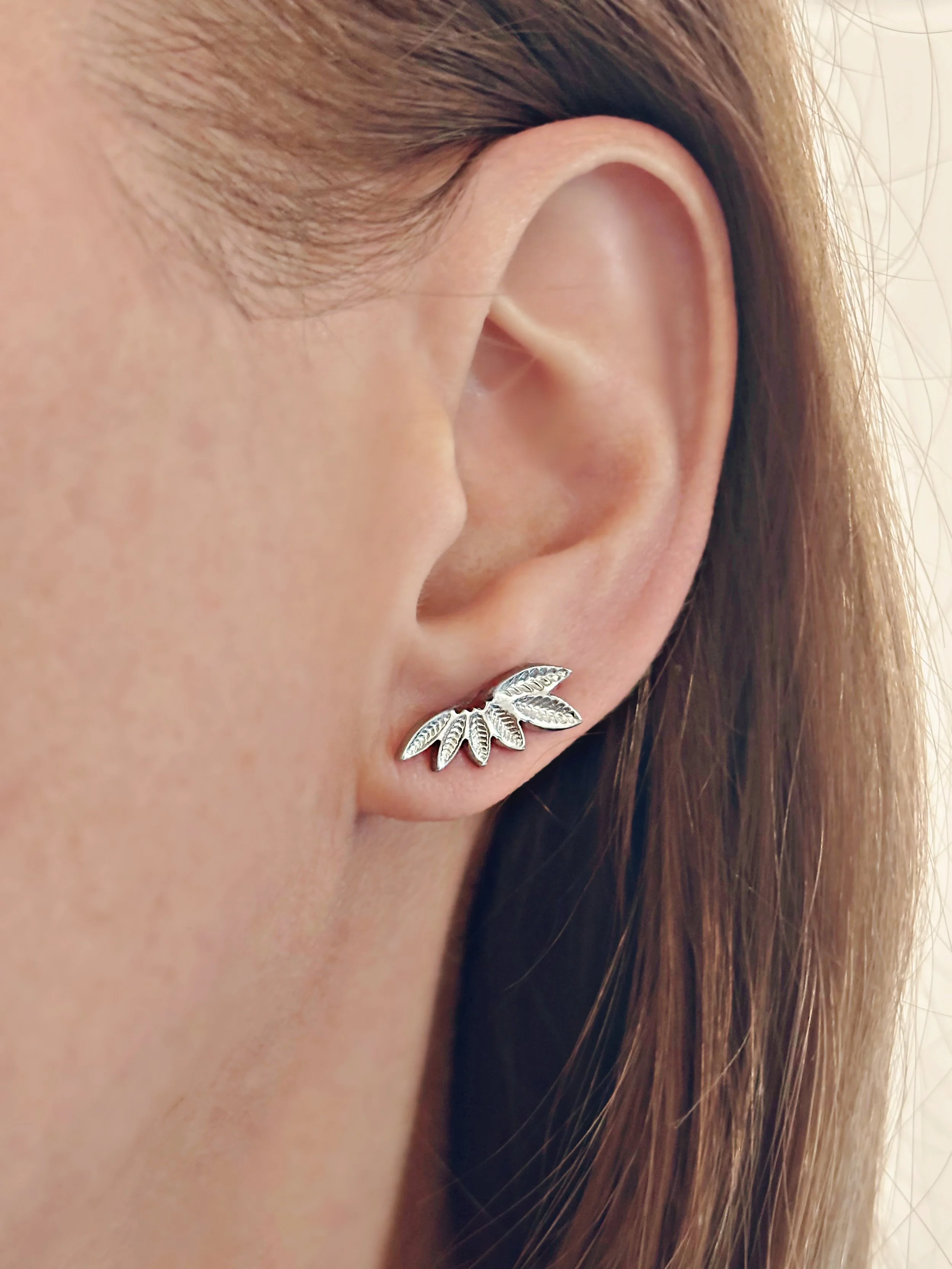 Boucles Flora portées, montrant leur design délicat en forme de feuilles.