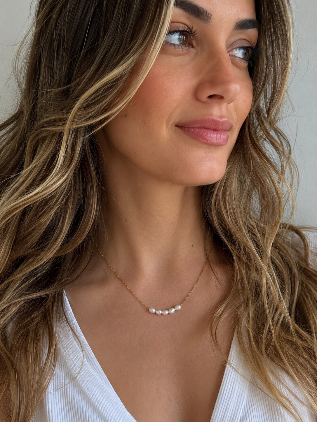 Femme portant le collier Cristy avec cinq perles d’eau douce sur une fine chaîne dorée. - Tokade