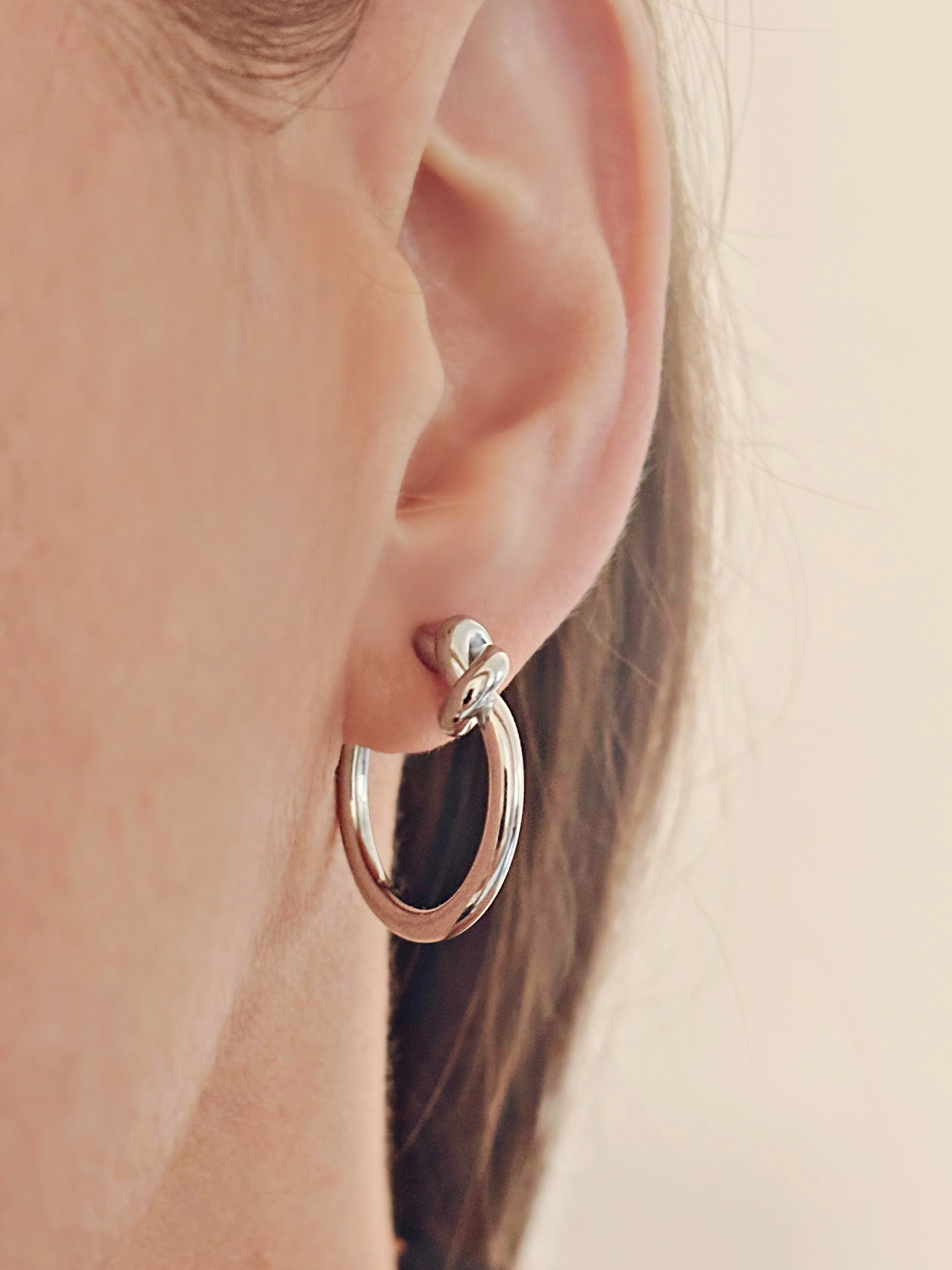 Boucles Noé portées, mettant en valeur le petit nœud et la forme circulaire élégante.