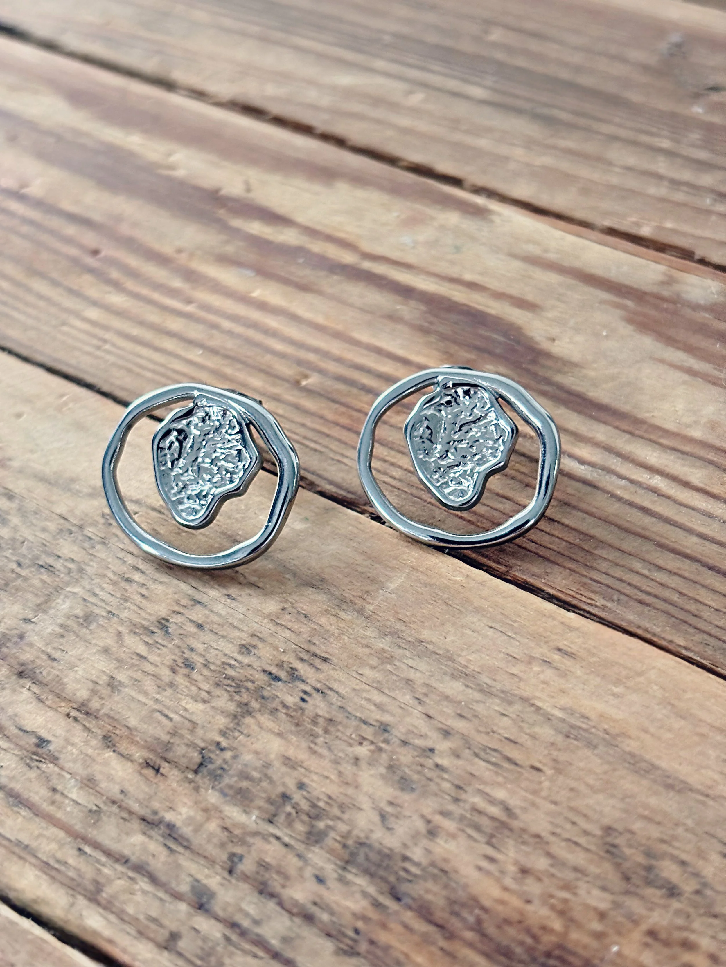 Boucles d’oreilles Aria posées sur une surface en bois, montrant leurs détails et leur éclat.