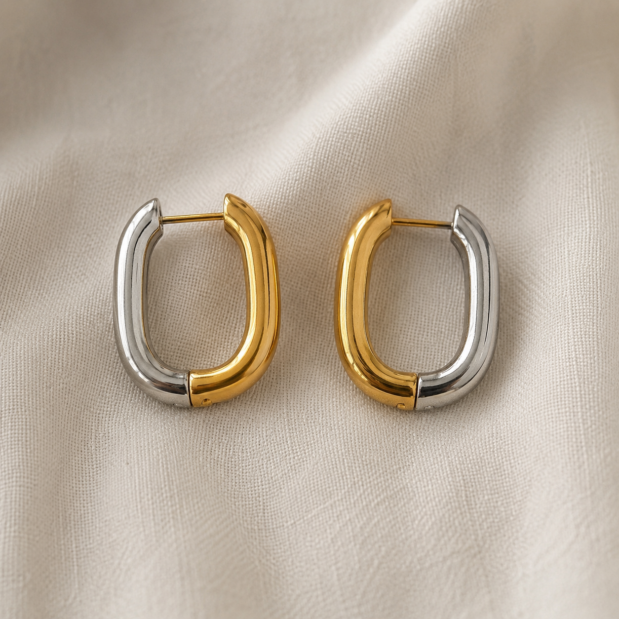 Boucles d’oreilles Daly deux tons en acier inoxydable doré et argenté sur tissu crème. - Tokade