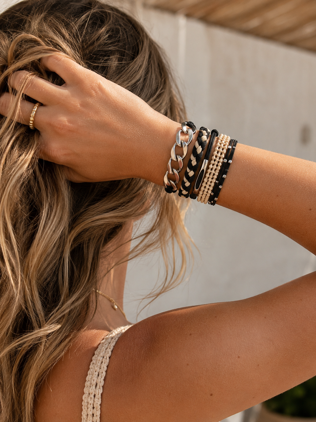 Lot de 5 élastiques à cheveux et bracelets 2-en-1 noir, crème et argent portés au poignet d’une femme tenant ses cheveux - Tokade