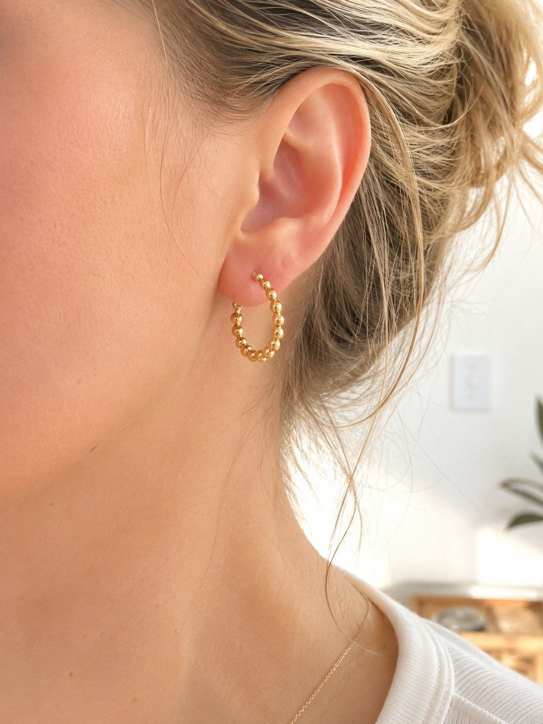 Femme portant les boucles d’oreilles Giorgia en acier inoxydable doré composées de petites billes.