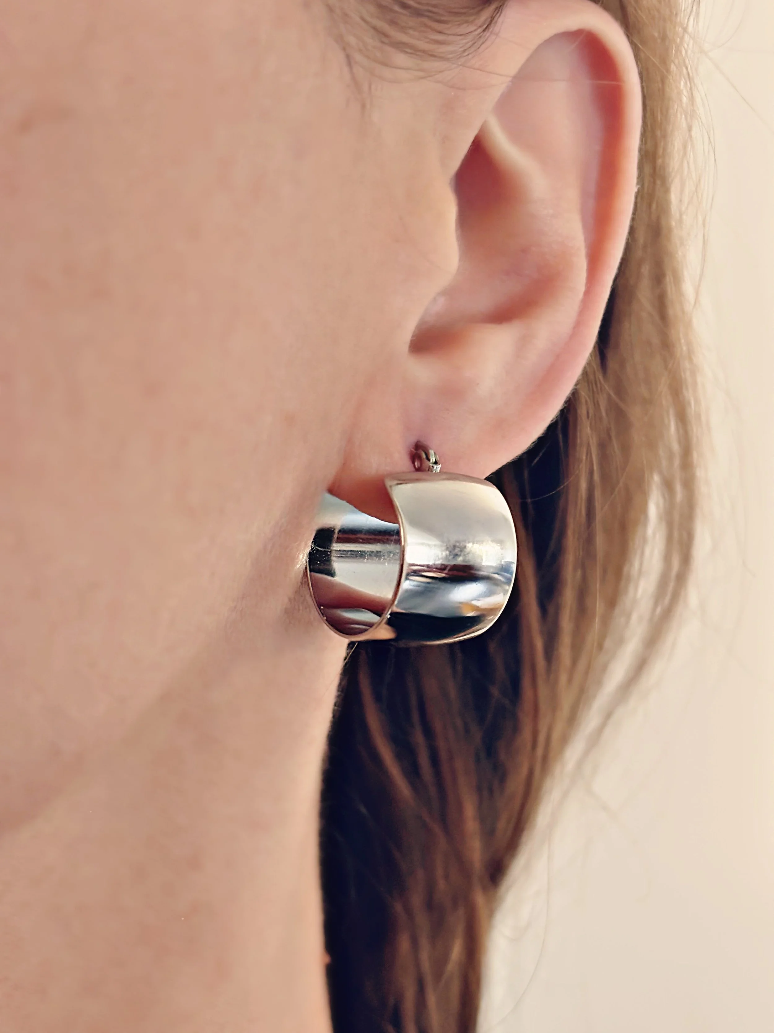 Boucles Nova portées, montrant leur brillance effet miroir.