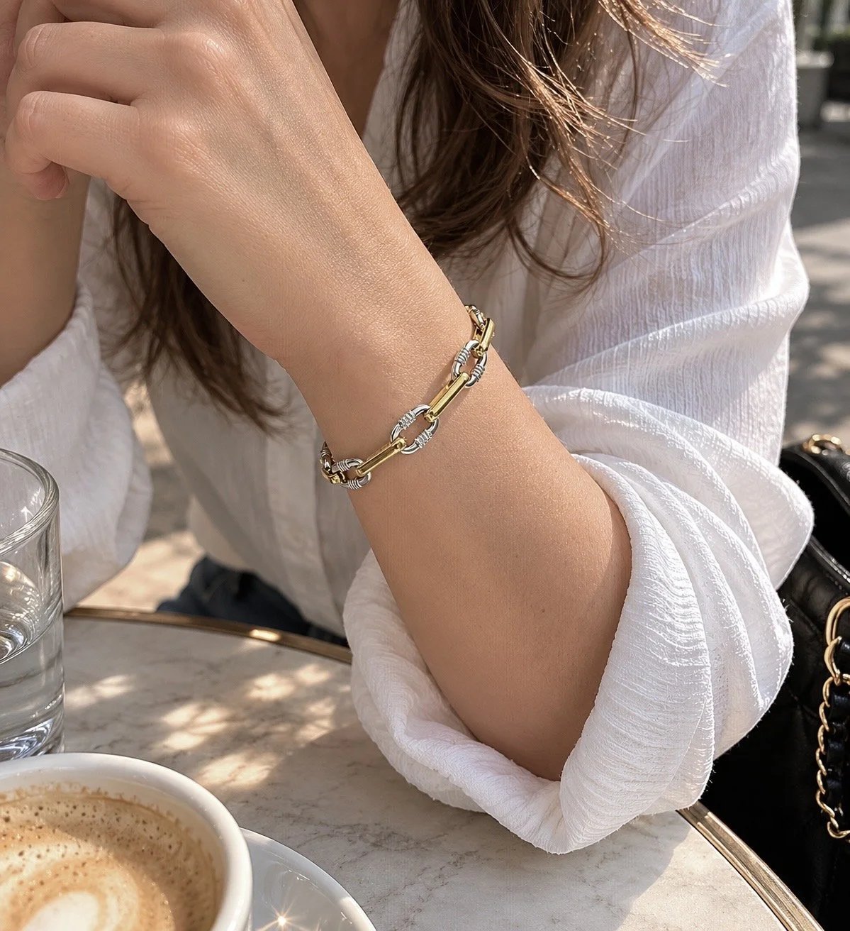 Bracelet Melba deux tons en acier inoxydable porté sur une terrasse ensoleillée. - Tokade