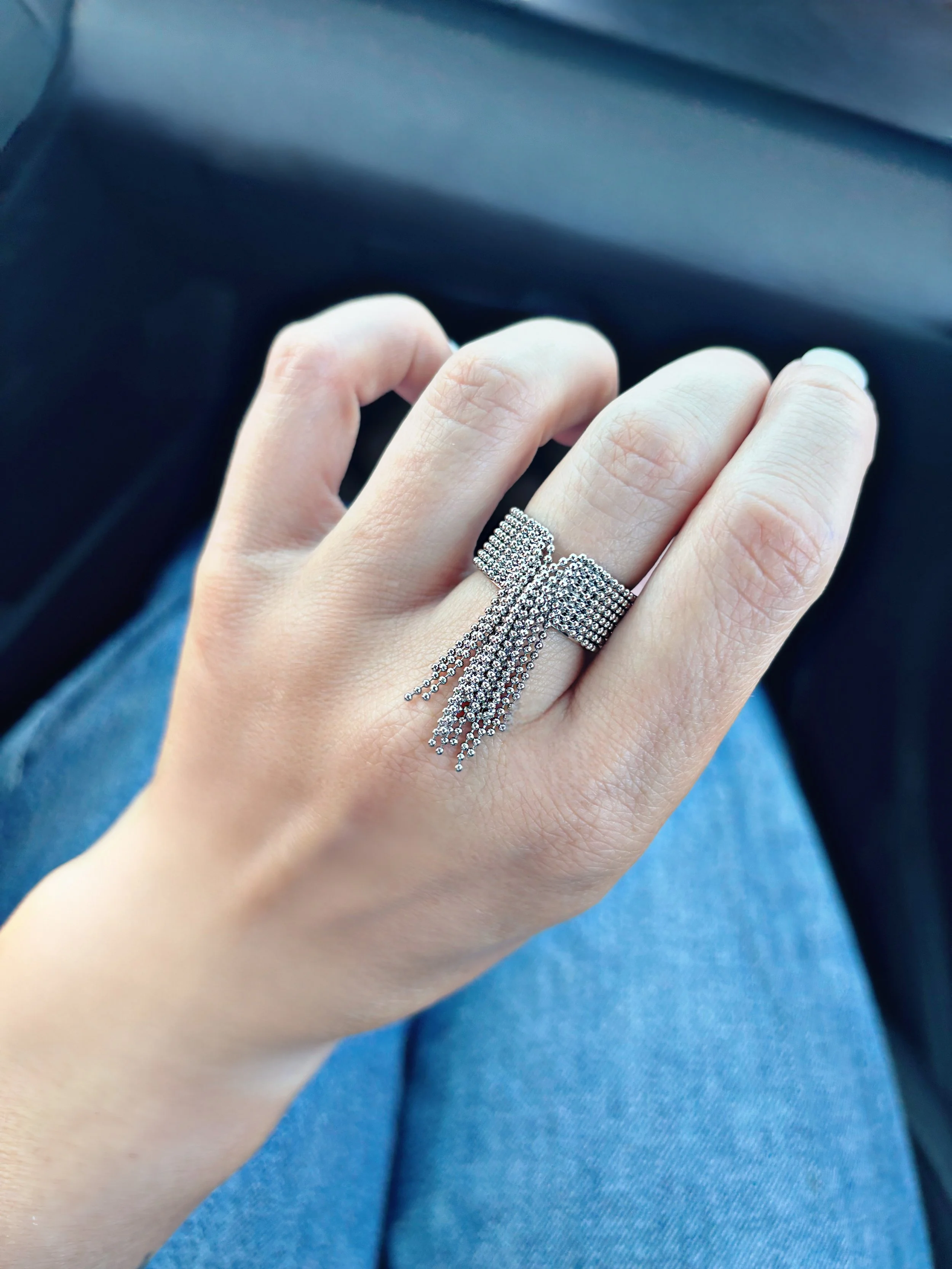 Bague en acier inoxydable argentée avec franges de chaînes, bijou original et tendance porté au doigt.